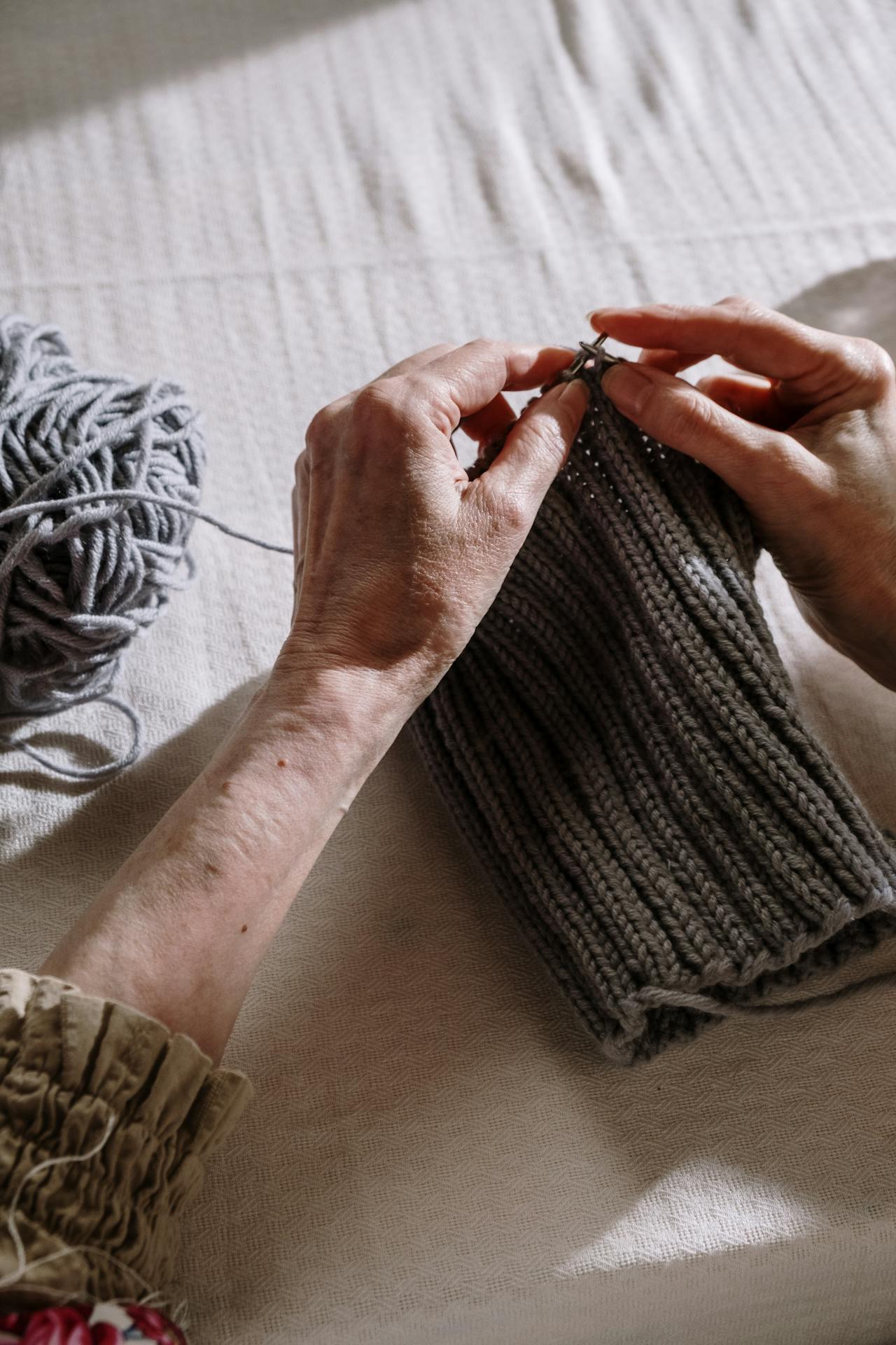 Close-up shot of an older woman knitting a gray thread | Source: Pexels