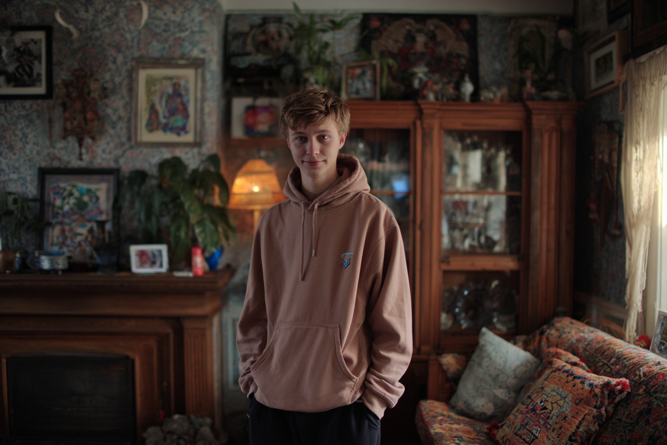A teen boy standing in a living room | Source: Midjourney