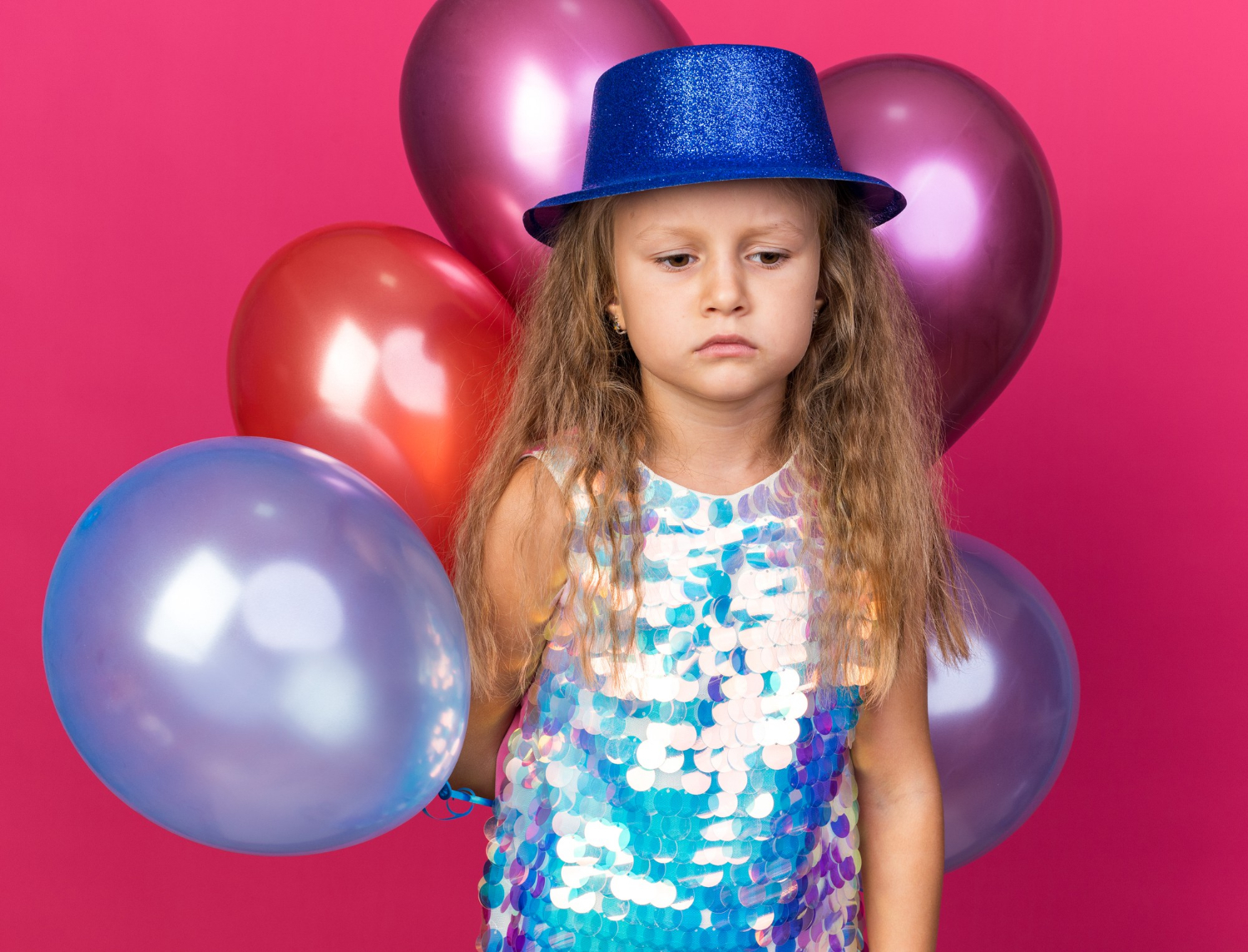 A sad little girl holding colorful balloons | Source: Freepik