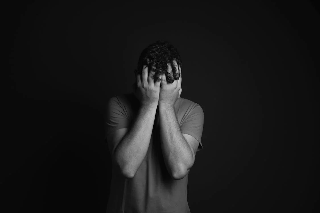 A sad man covering his face | Source: Pexels