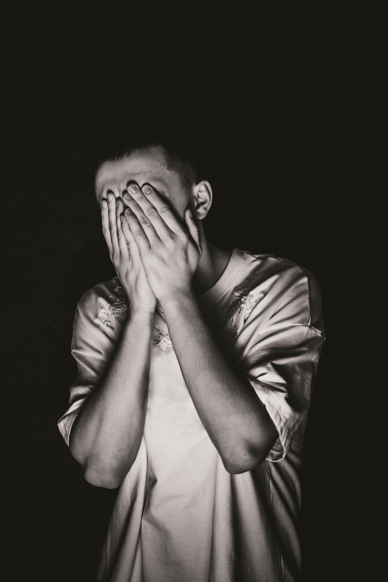 Grayscale shot of a man covering his face | Source: Pexels