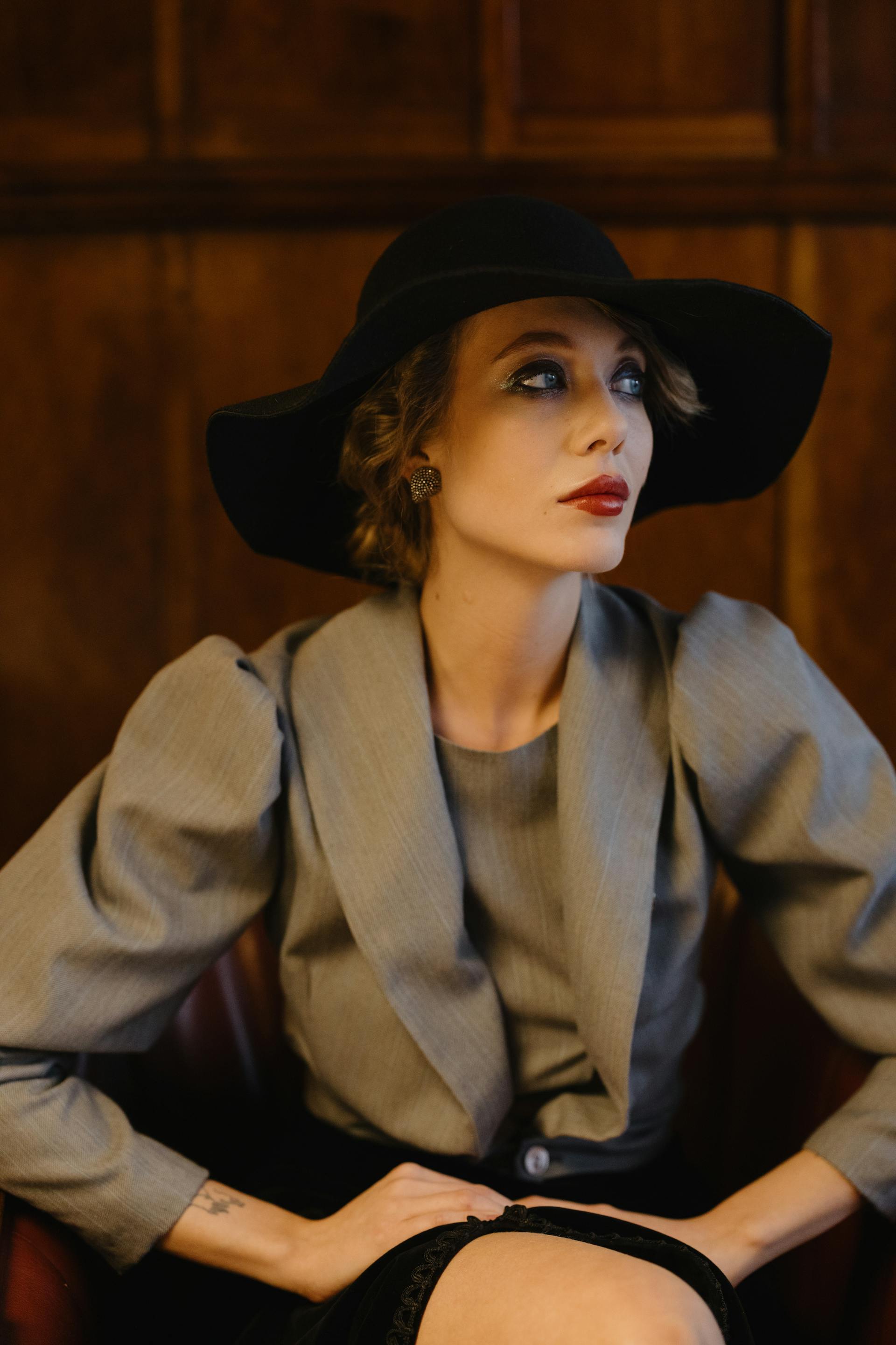 A fashionable woman with red lipstick and a black hat looking off to the side | Source: Pexels