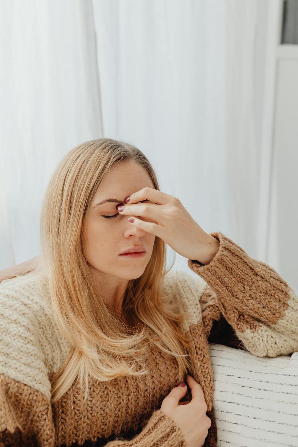 A frowning woman rubbing her eyebrows ⏐ Source: Pexels