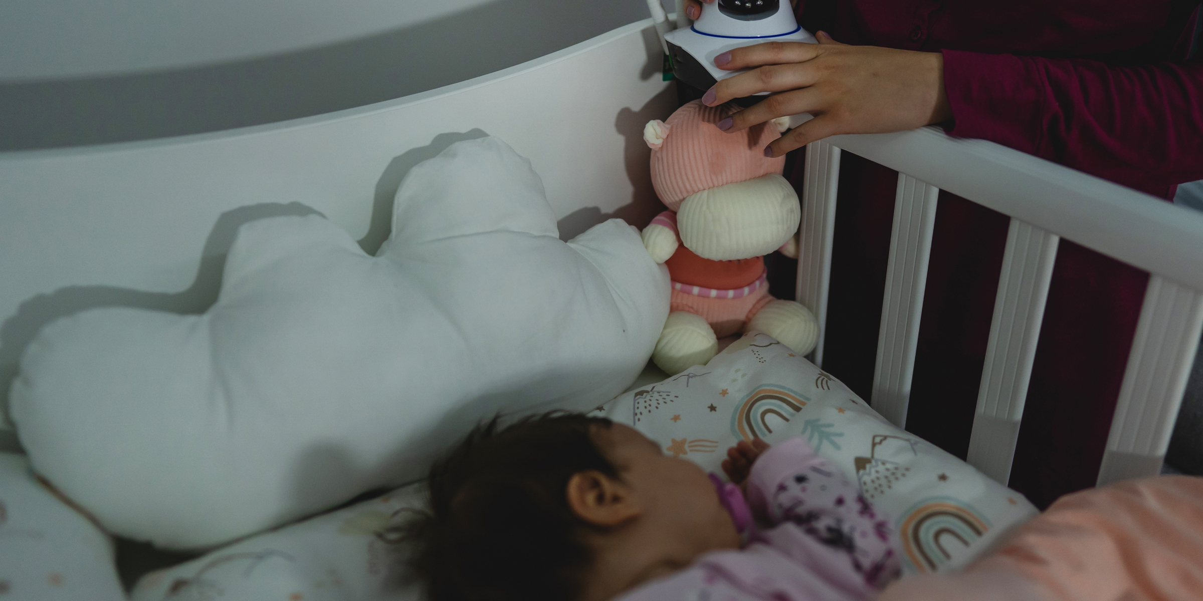 A woman placing a camera on a baby's crib | Source: Shutterstock
