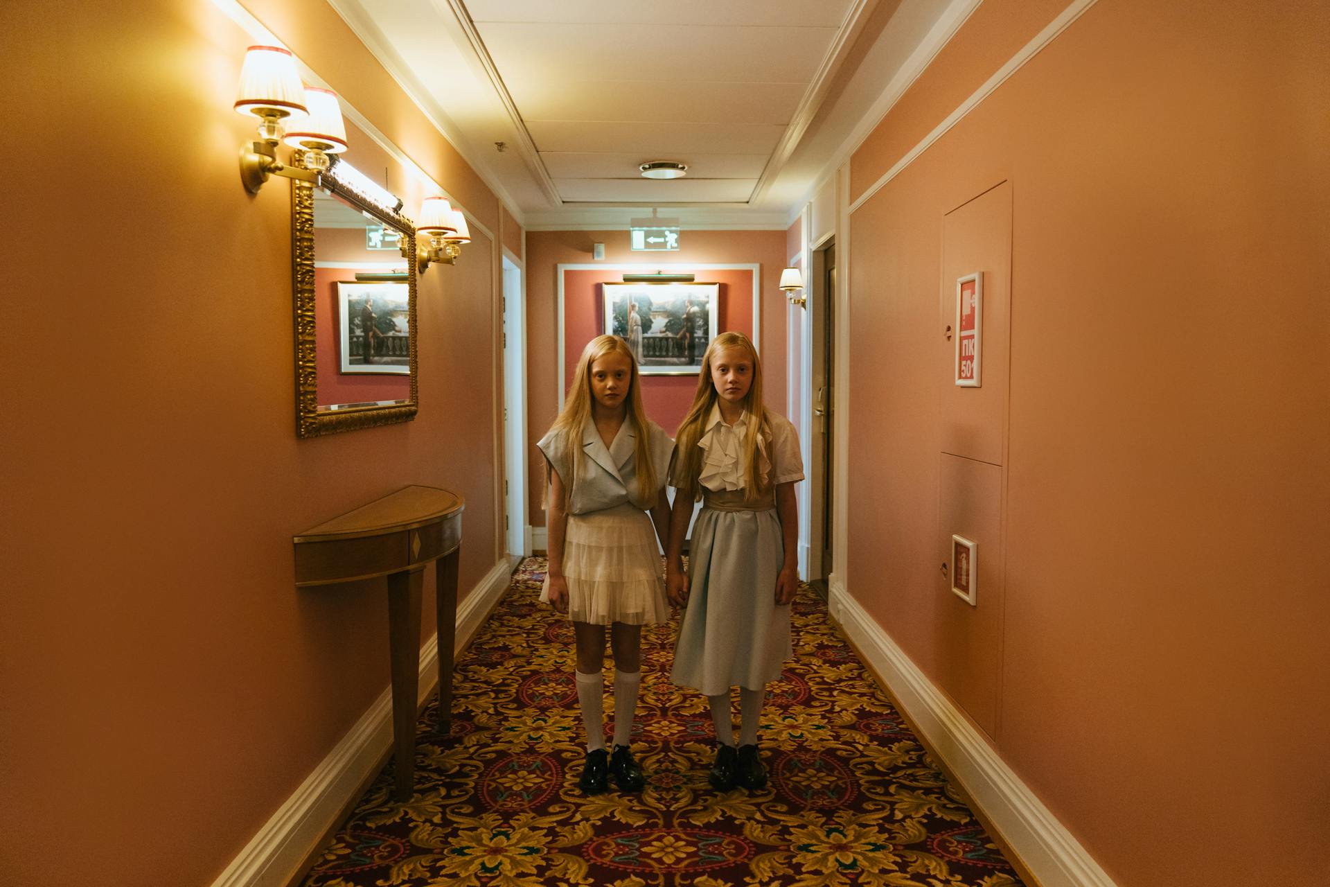 Twin sisters holding hands and standing in the hallway | Source: Pexels