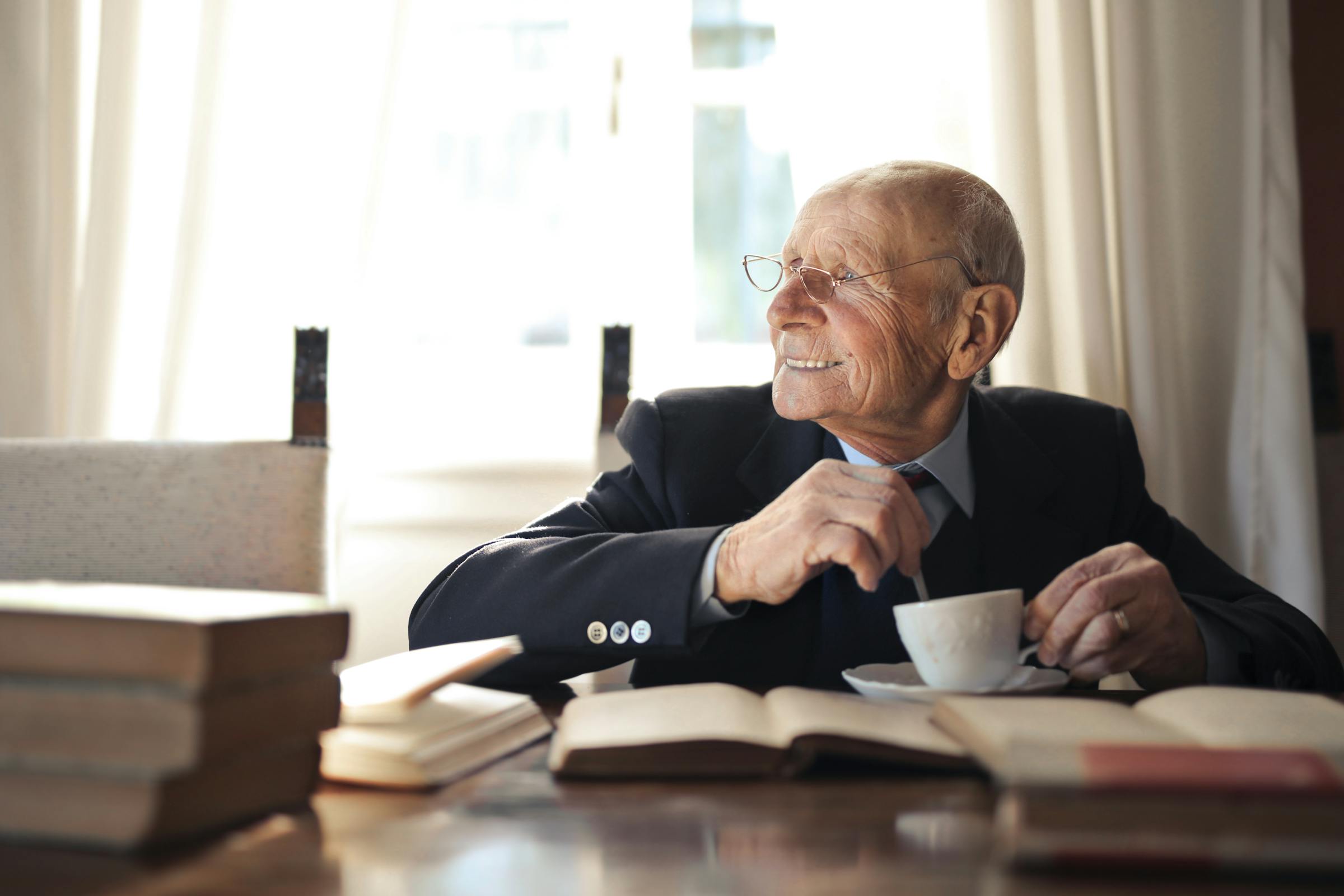 Un hombre sentado en un escritorio de oficina, sonriendo, con libros sobre la mesa | Fuente: Pexels