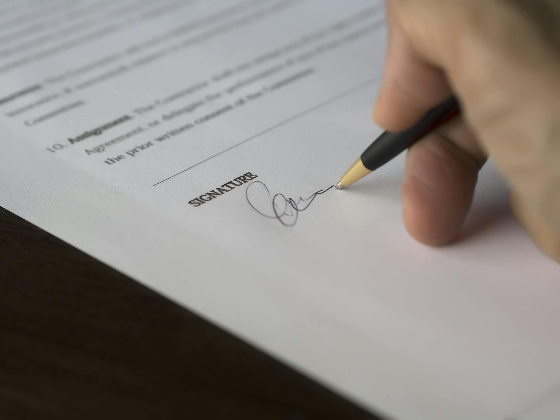 A woman signing a document while giving her daughter up for adoption | Source: Pexels