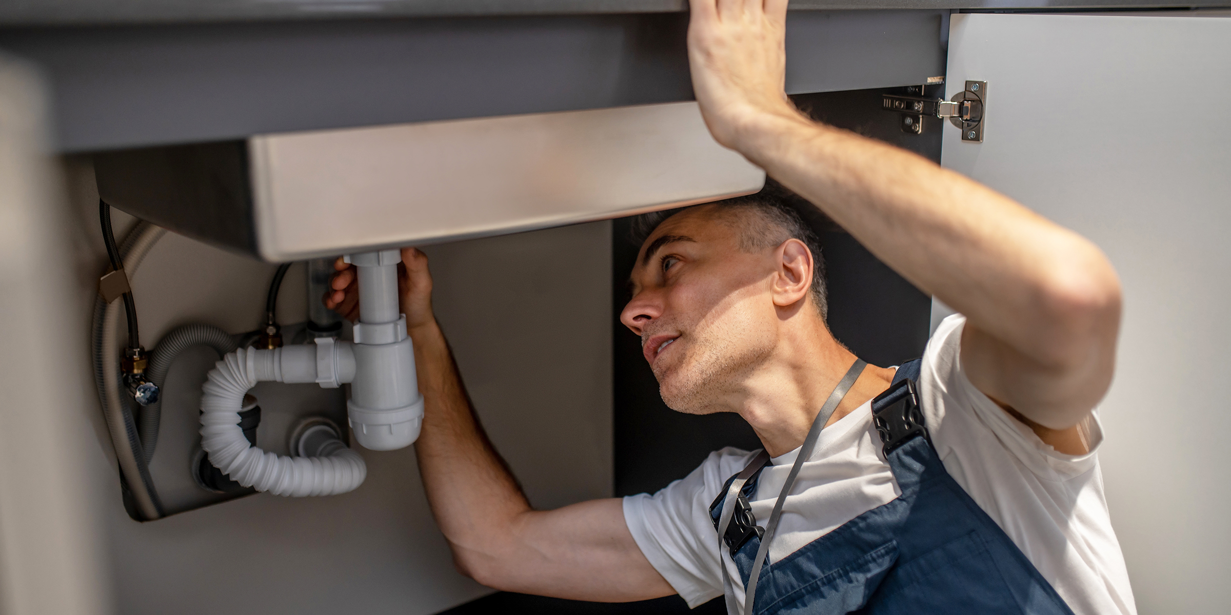 A man fixing a kitchen sink | Source: Shutterstock