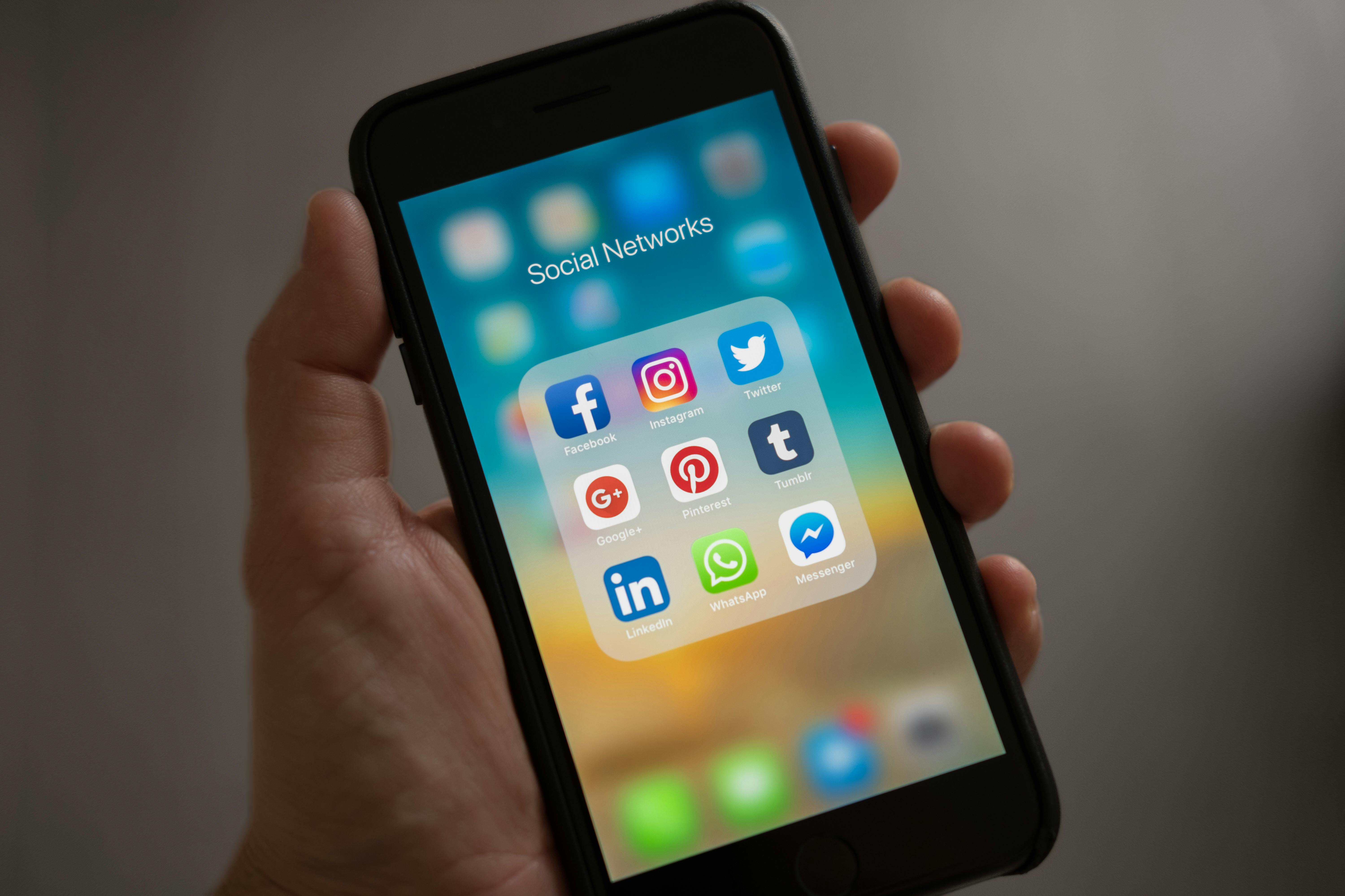 A person holding a cellphone open to a social media folder | Source: Pexels