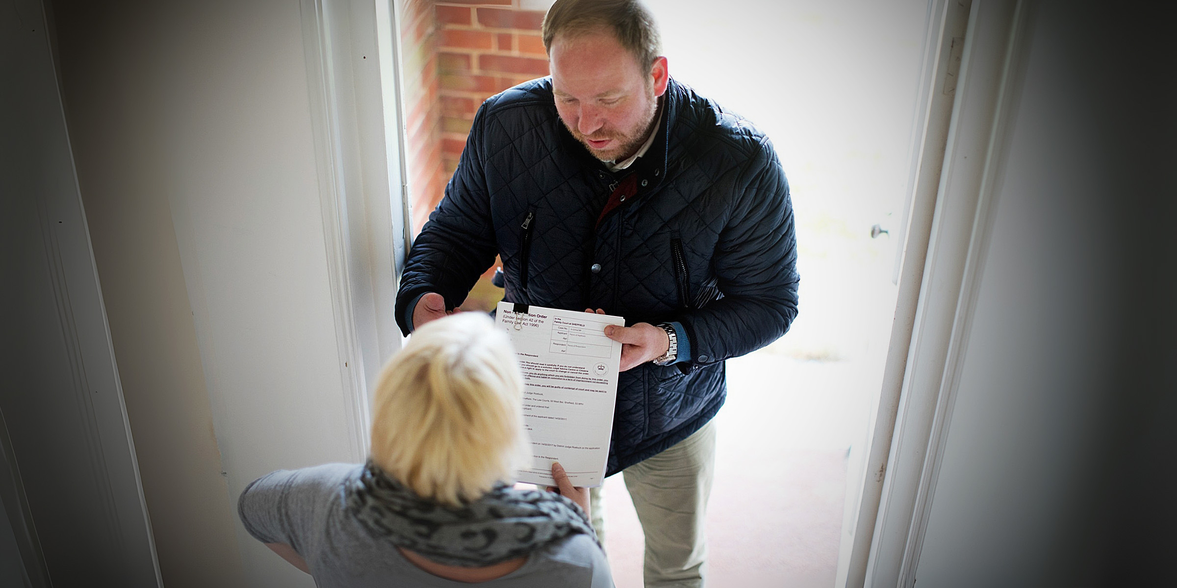 A delivery person handing a document to a woman | Source: Flickr