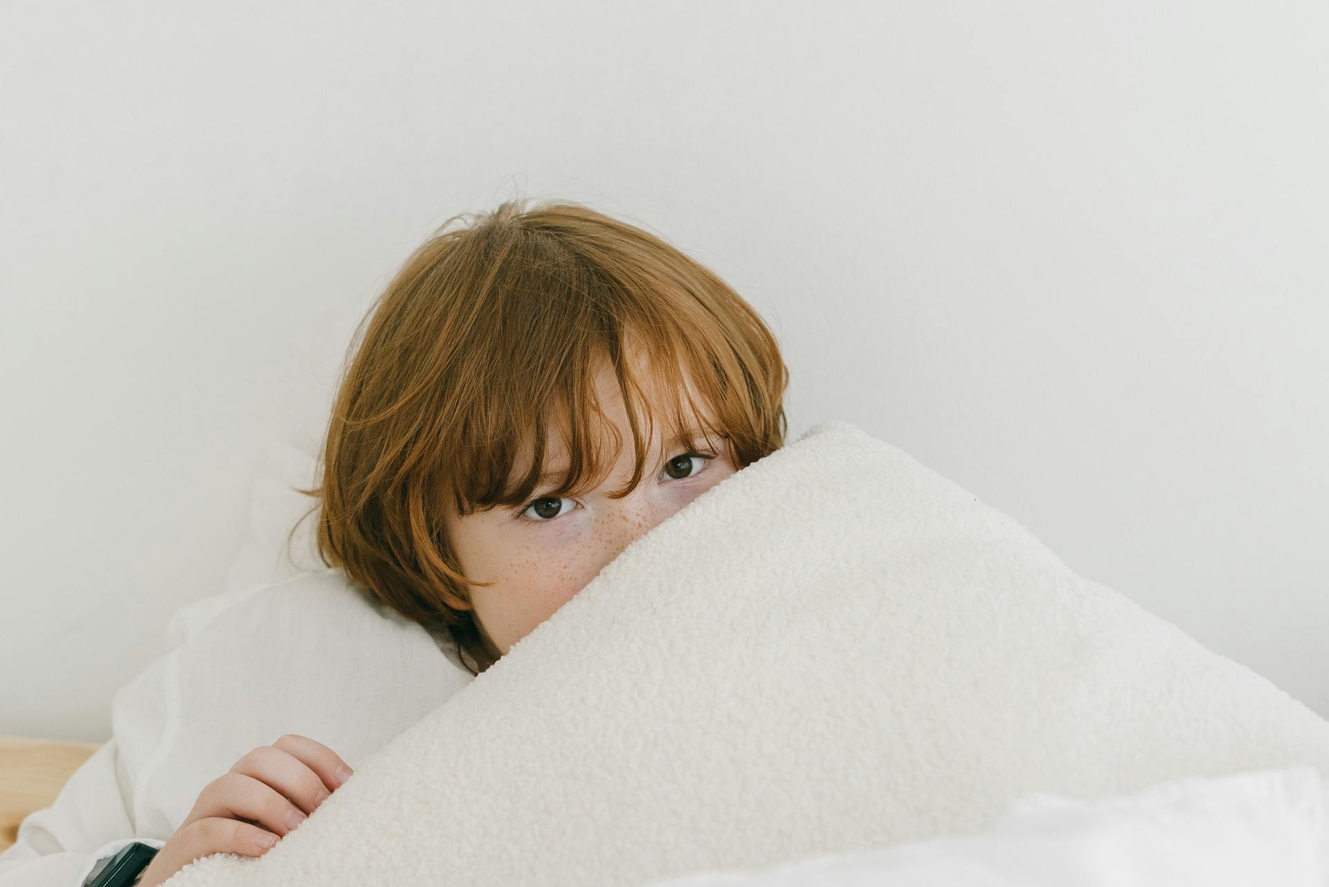 A boy lying under his blanket | Source: Pexels