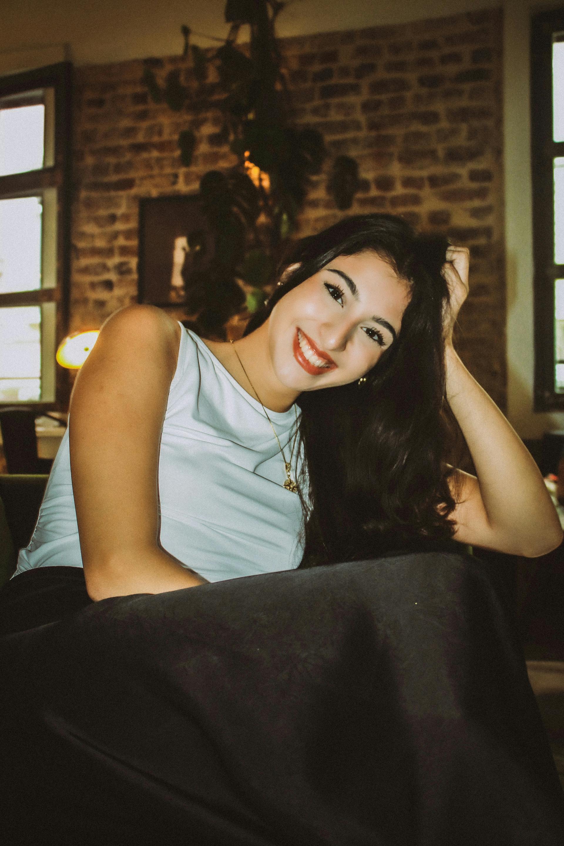 A woman with long hair sitting in a chair and smiling | Source: Pexels