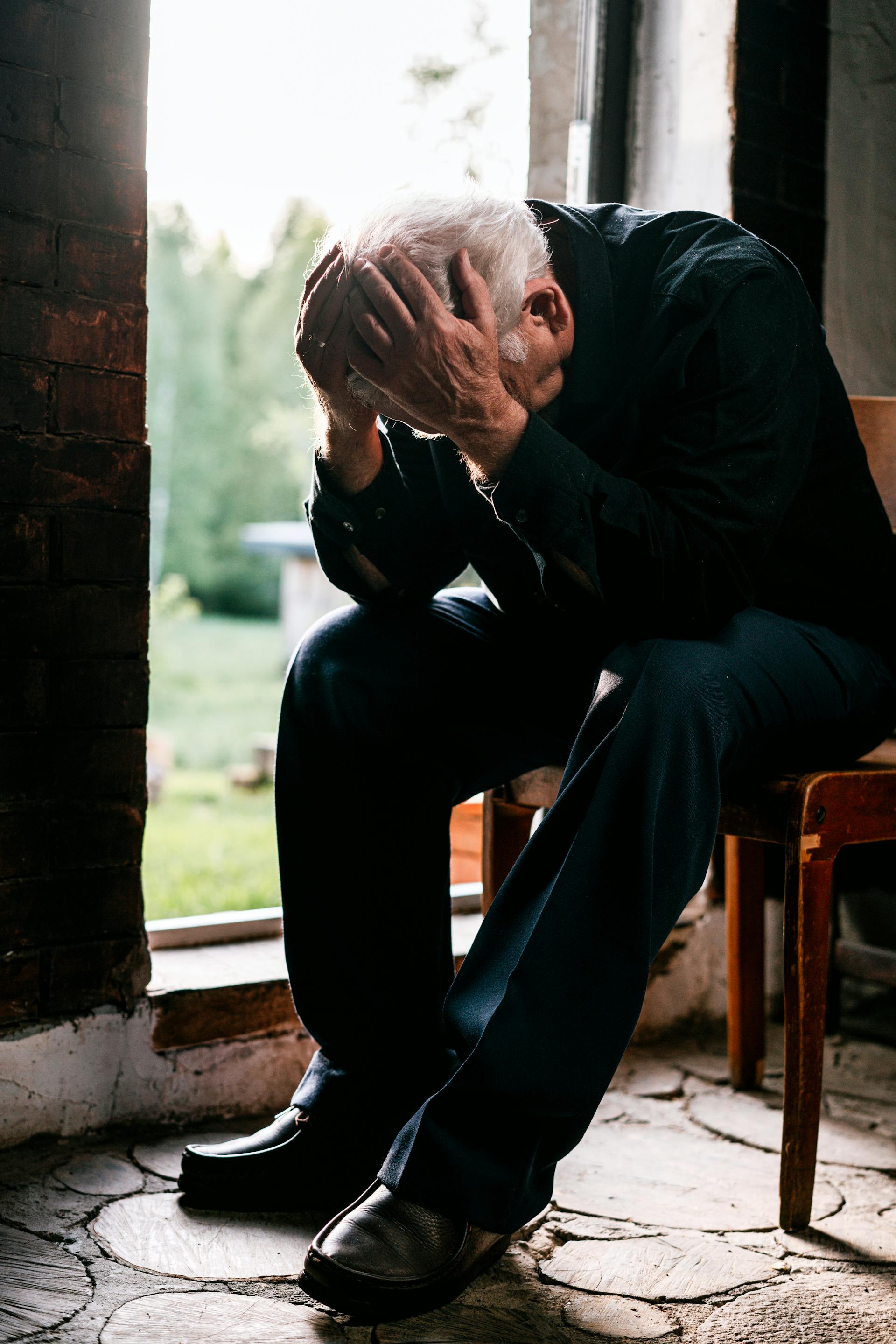 A very sad man sitting on a wooden chair | Source: Pexels