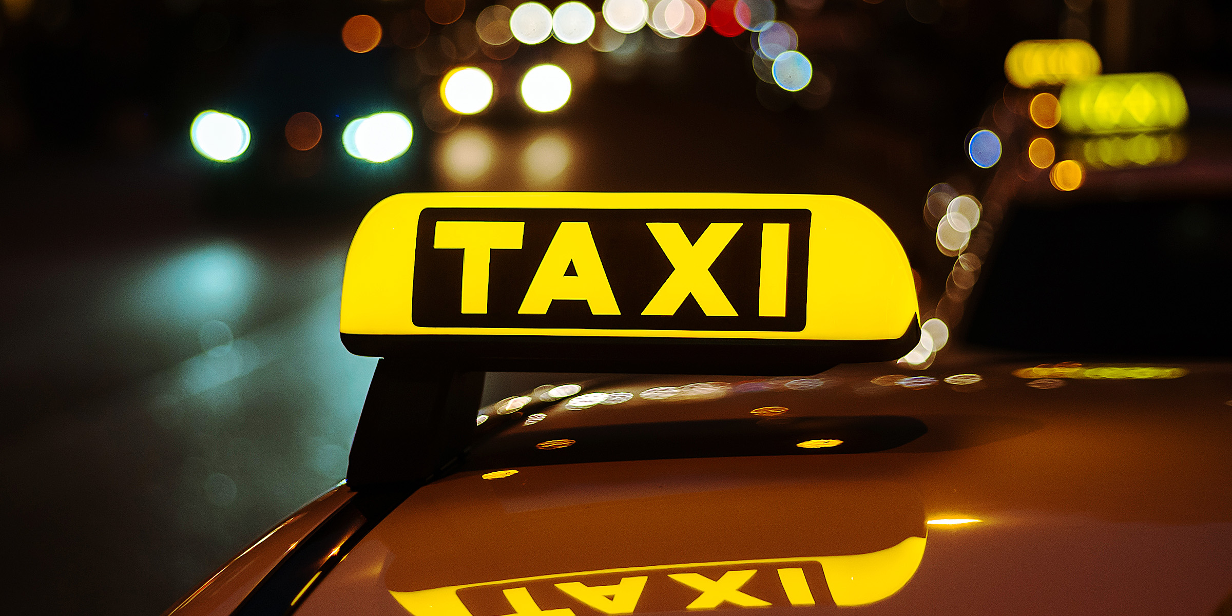 A yellow and black sign of a taxi placed on top of a car | Source: Freepik