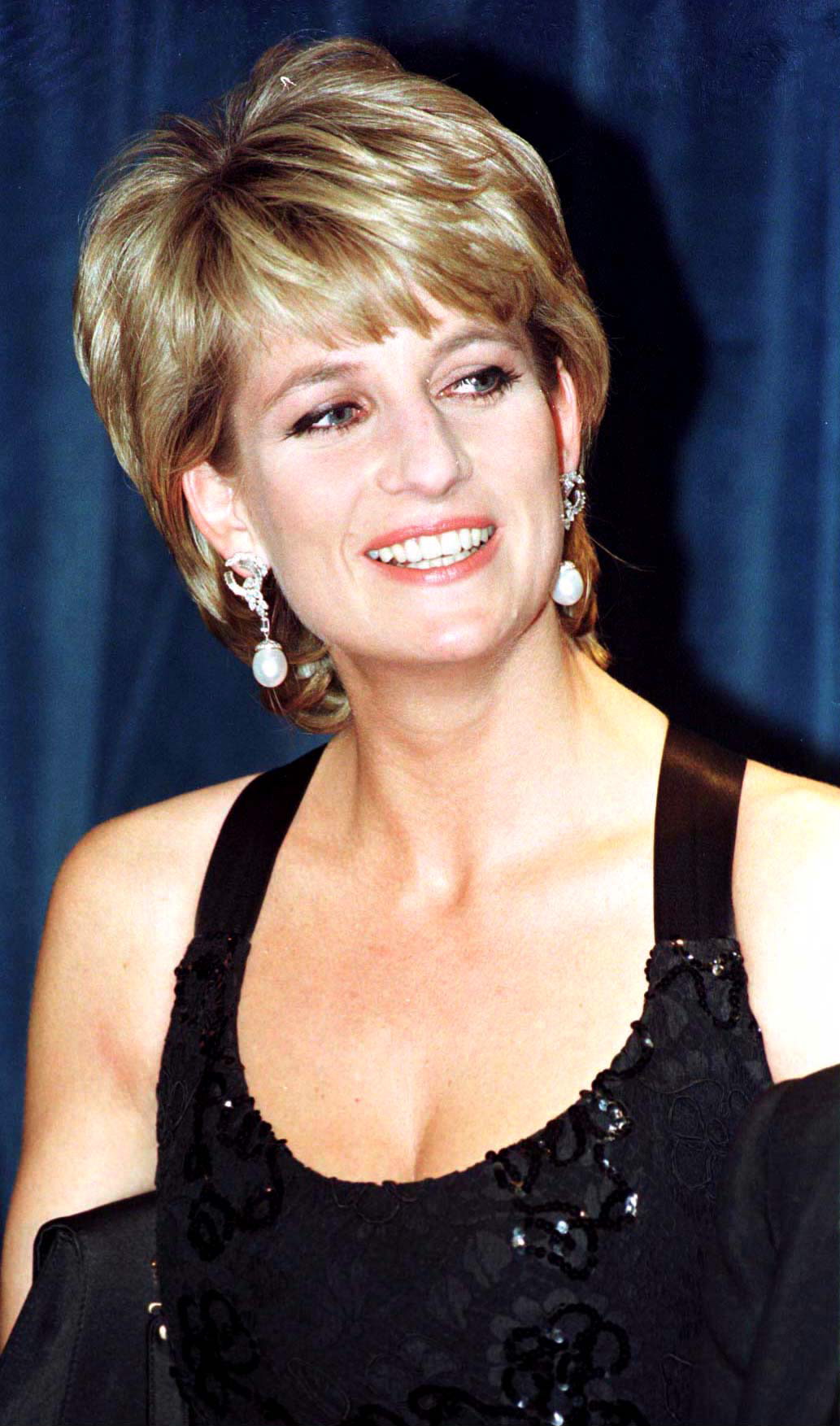 The English princess, who turned 35 in 1996, attended a humanitarian awards ceremony in New York with an elegance that felt both modern and timeless. Her short, feathered hair, radiant smile, and classic black evening gown with subtle sequins captured a regal poise that blended glamour with unmistakable warmth. She carried herself like royalty — not just in title, but in presence.