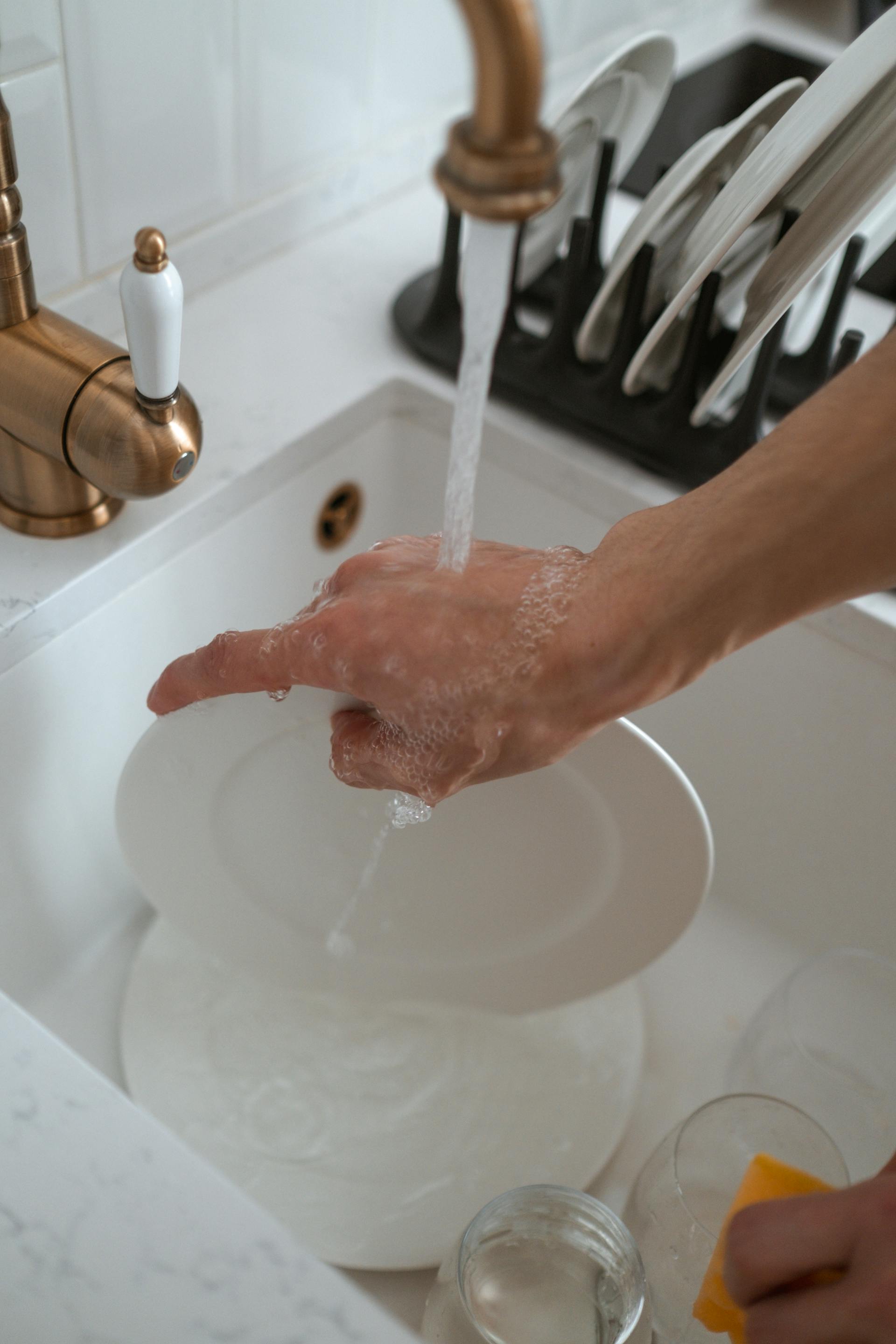 A close-up shot of a woman rinsing dishes | Source: Pexels