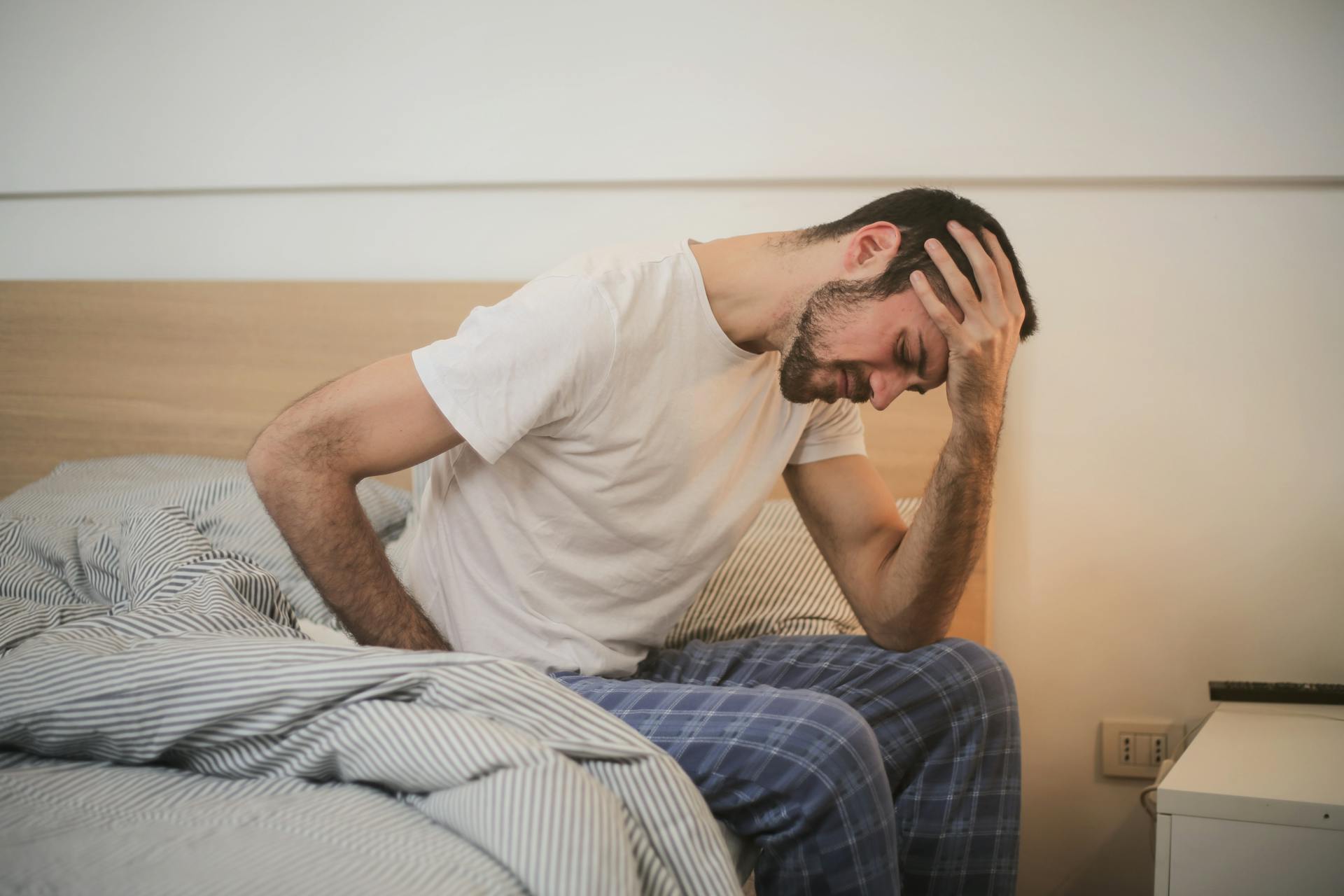 A man sitting on the side of the bed | Source: Pexels