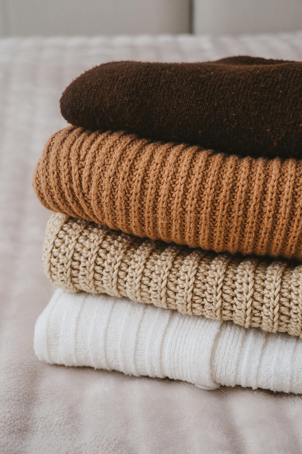 A stack of folded sweaters on the bed | Source: Pexels