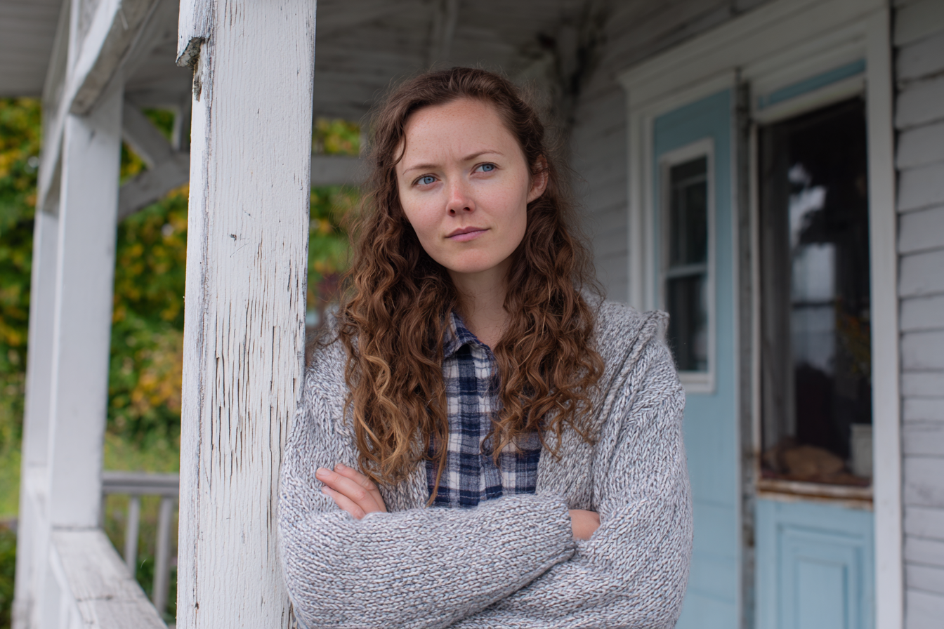 A woman standing on a porch | Source: Midjourney