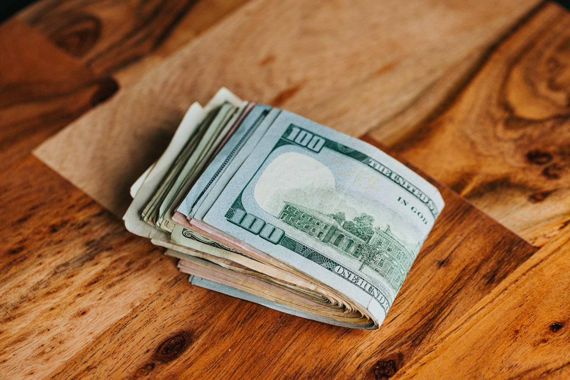 Dollar bills on a wooden surface | Source: Unsplash