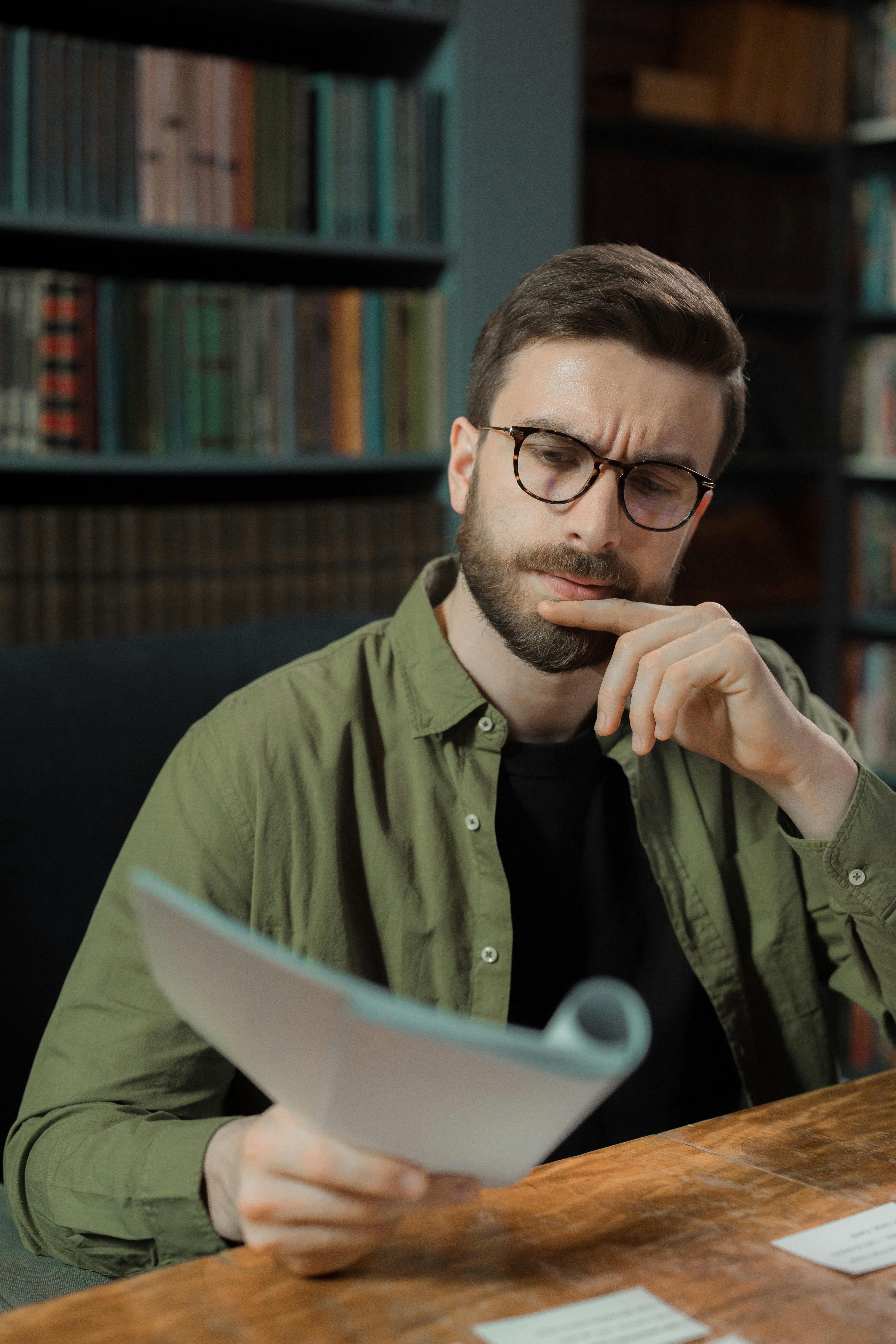 Young man in deep thoughts reading a document | Source: Pexels