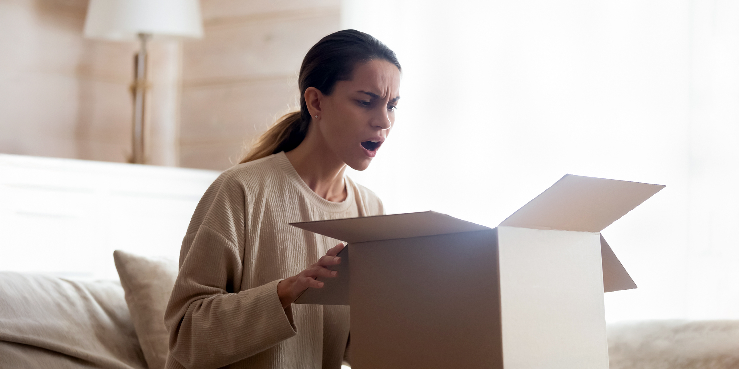 Woman opening a box in disbelief | Source: Shutterstock