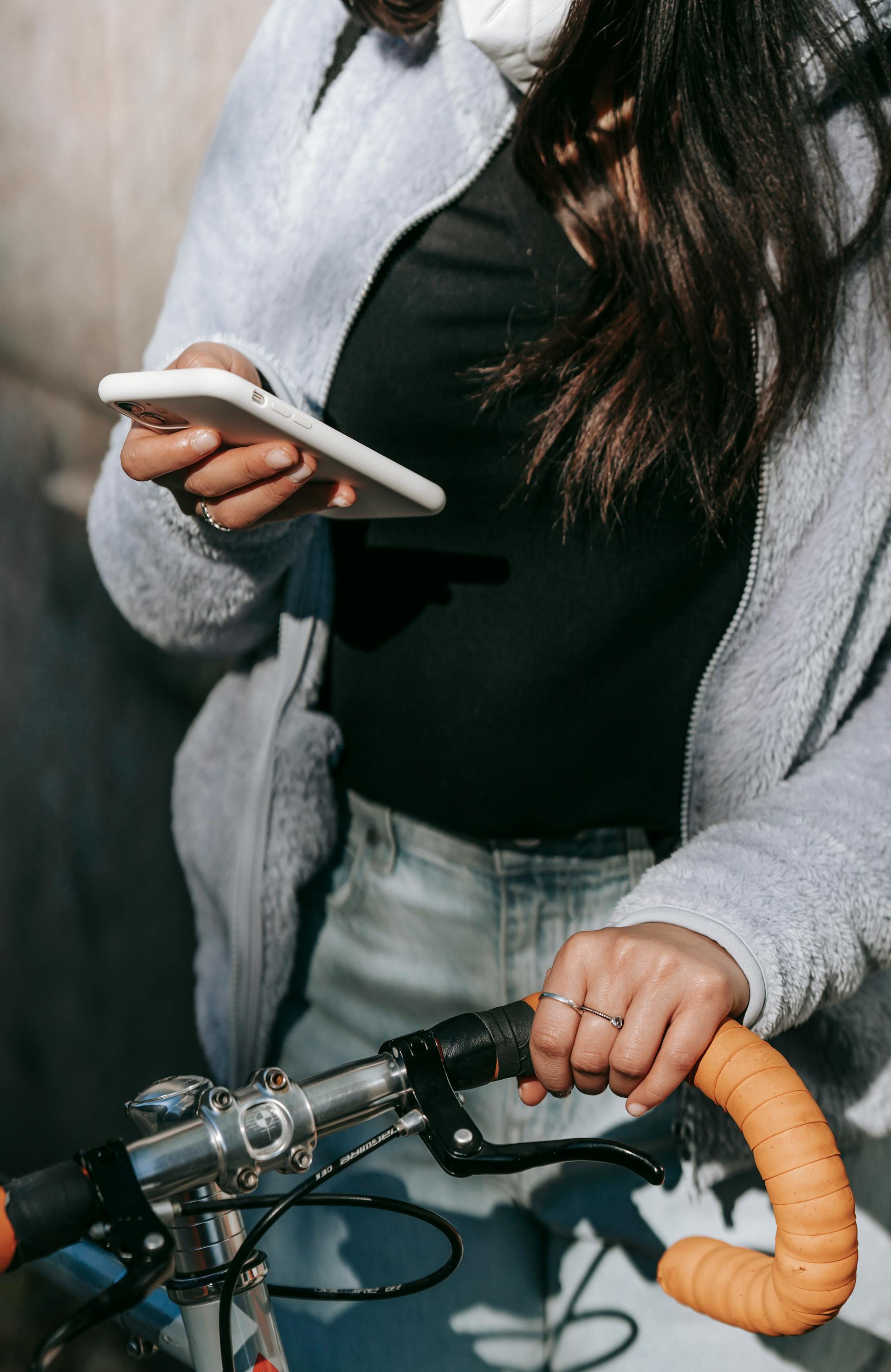A young woman using her phone while holding her bicycle's handle | Source: Pexels