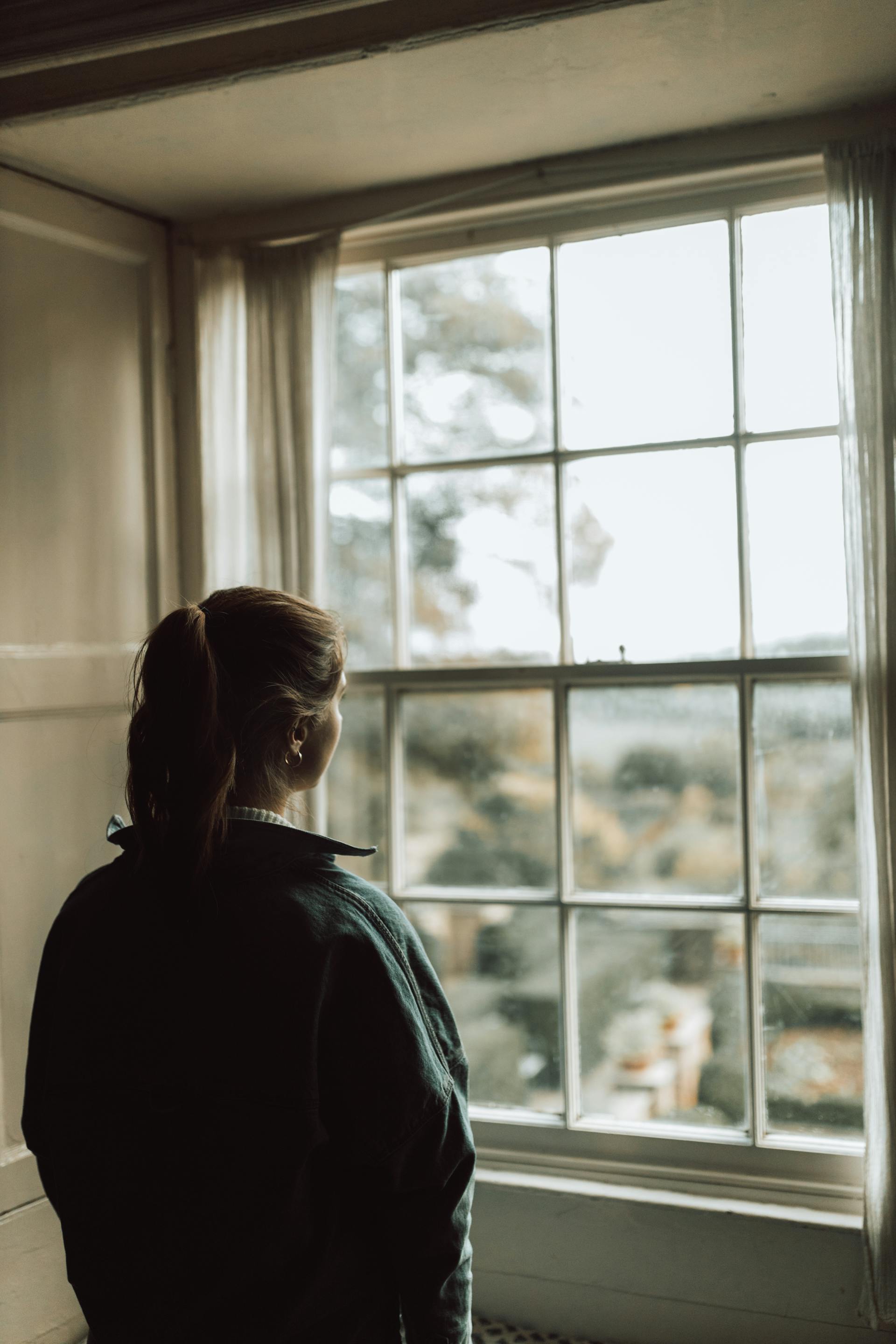 A woman looking outside her window | Source: Pexels