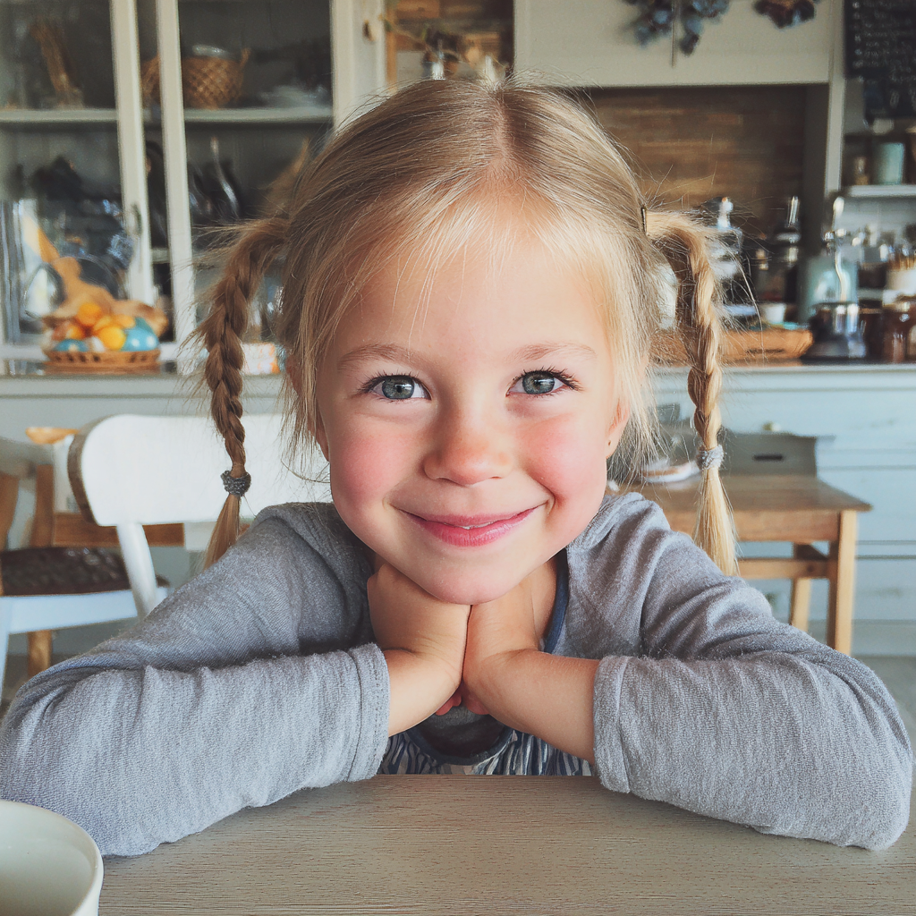 A smiling little girl sitting at a breakfast table | Source: Midjourney