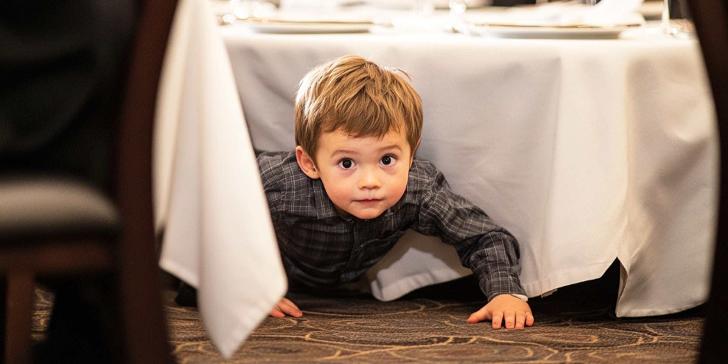 A child crawling out from under a table | Source: The Celebritist