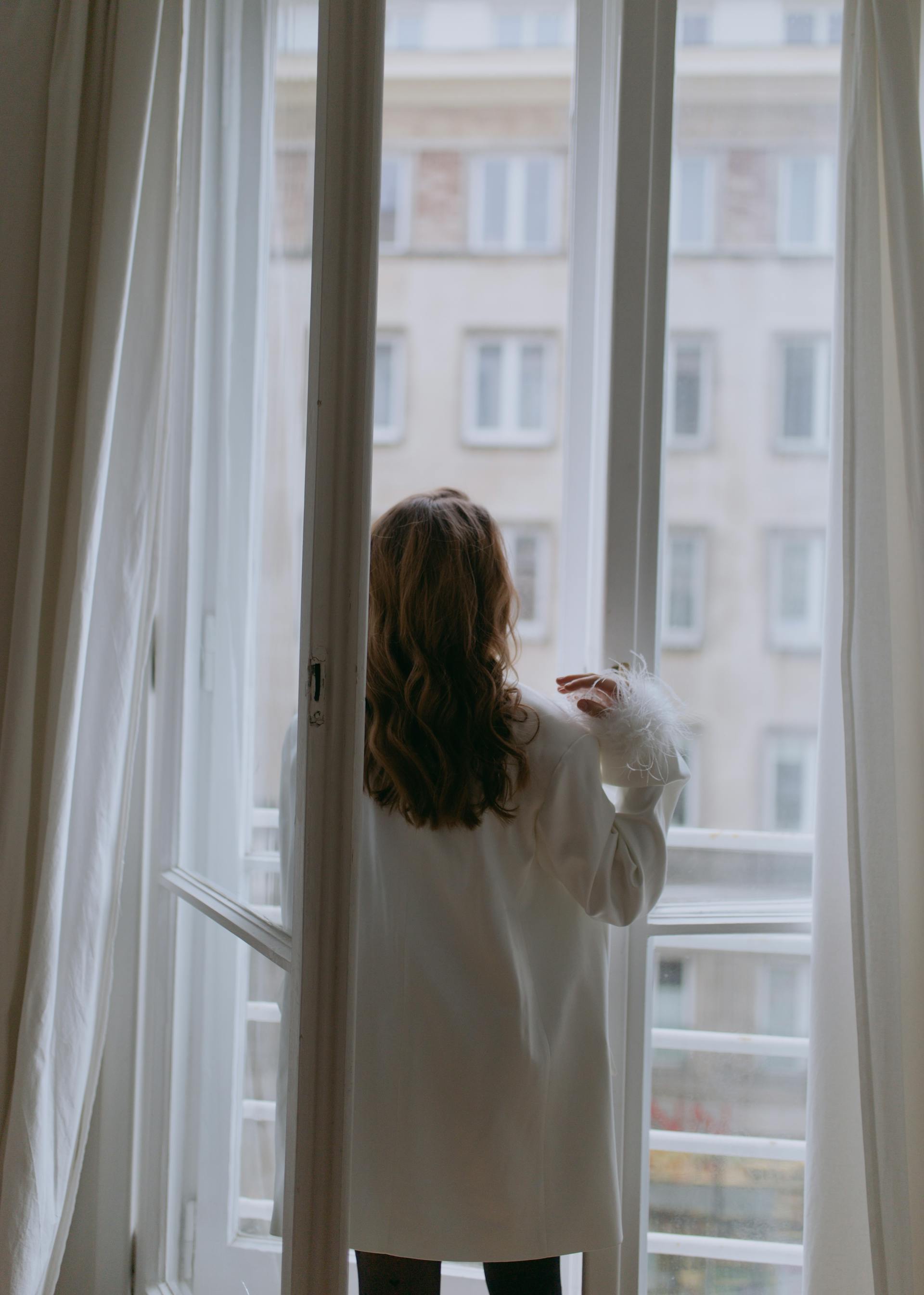 A woman standing next to an open window | Source: Pexels