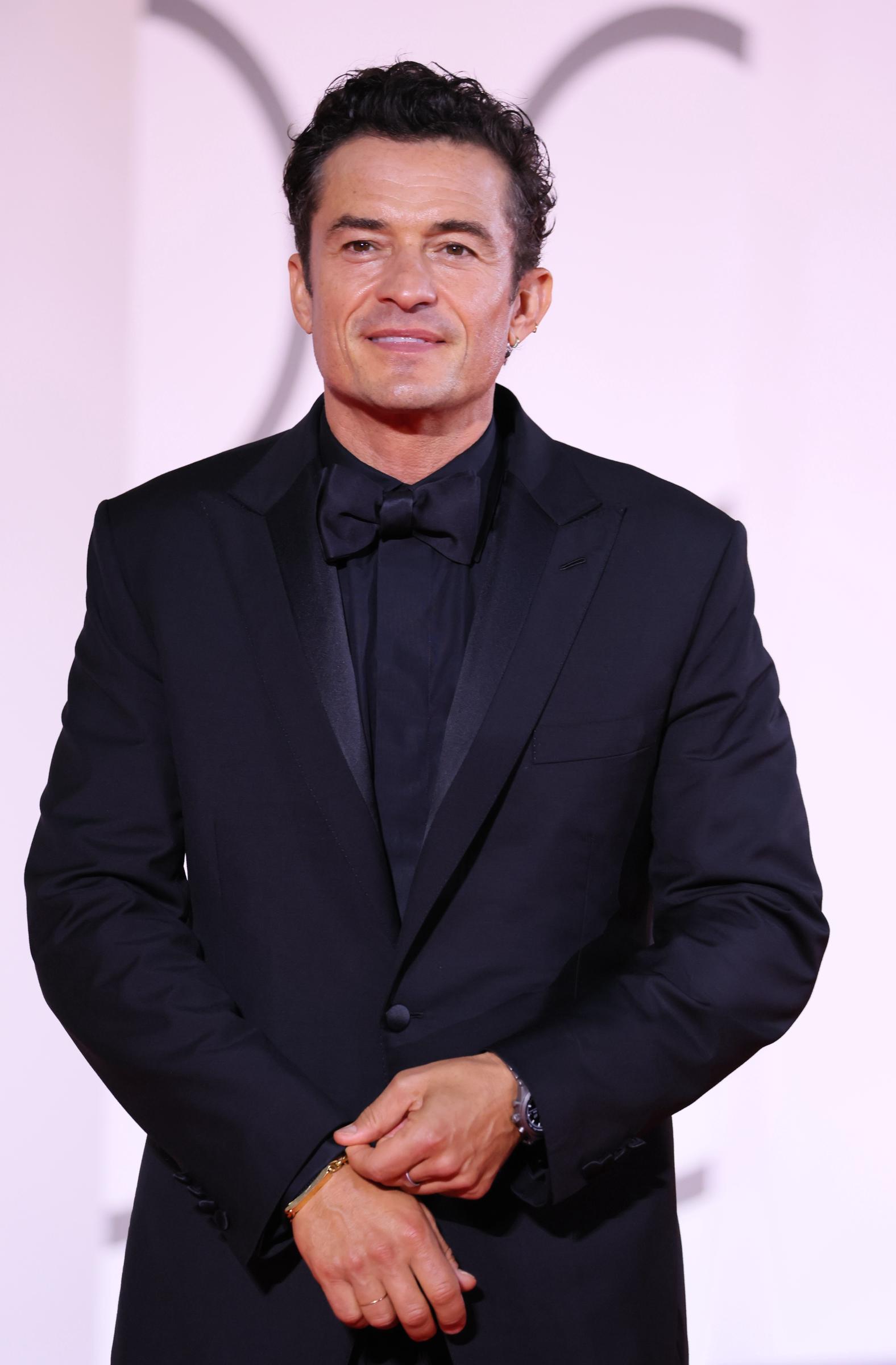 Orlando Bloom smiles for photographers in his black tuxedo, with satin lapels and an oversized bow tie giving the look a formal finish. | Source: Getty Images