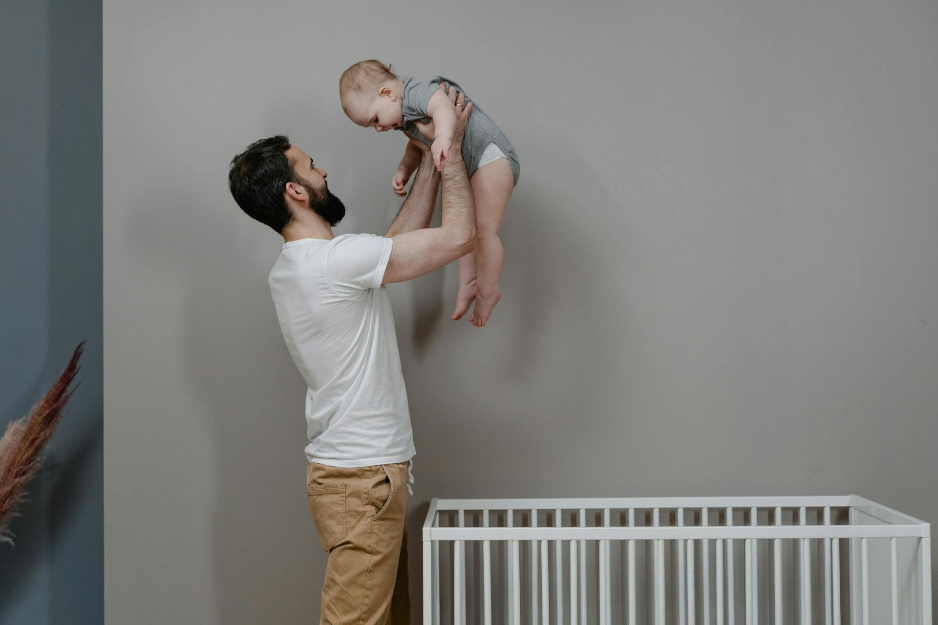 A man lifting a baby out of a crib | Source: Pexels