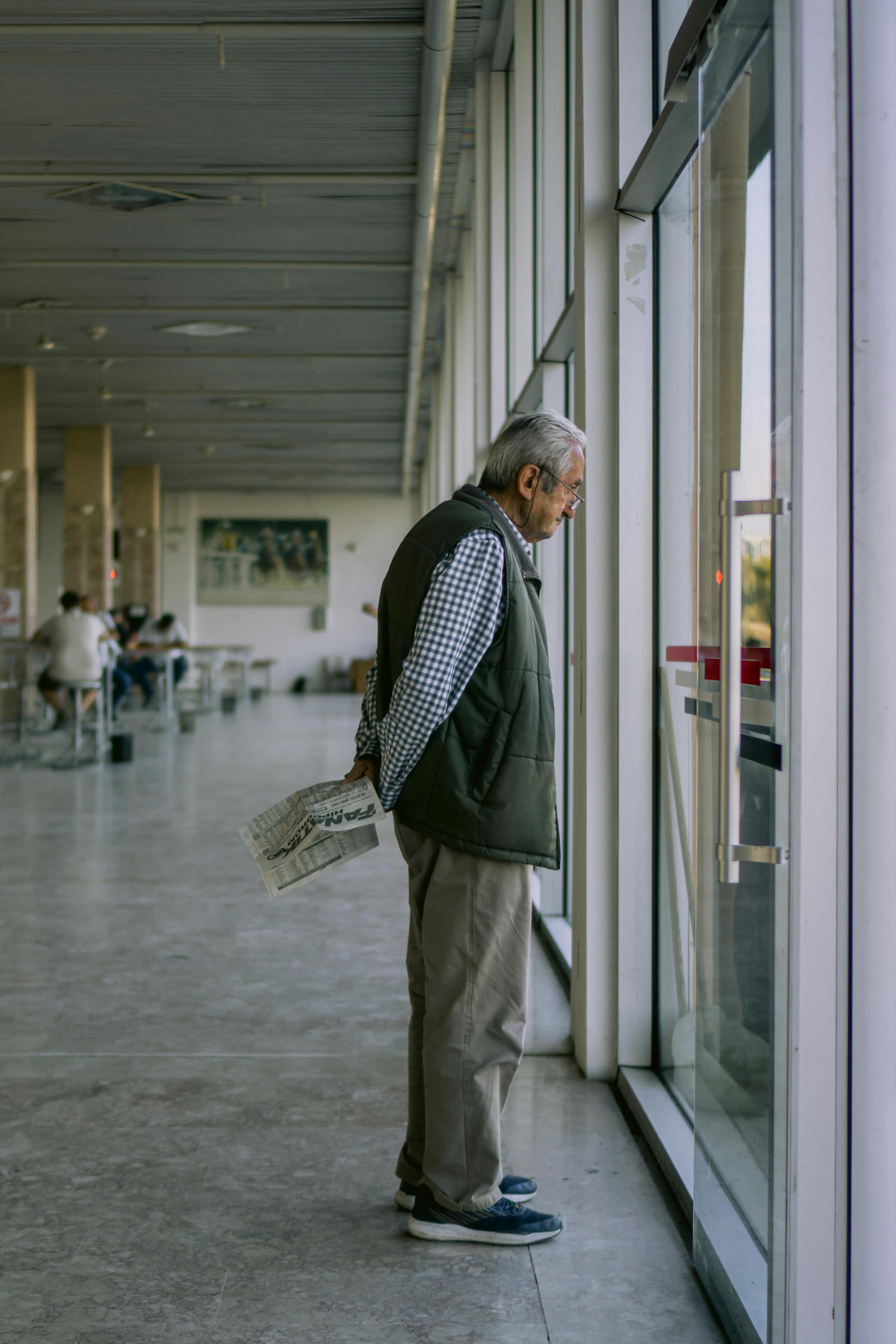 Senior man looking through the window at an airport | Source: Pexels