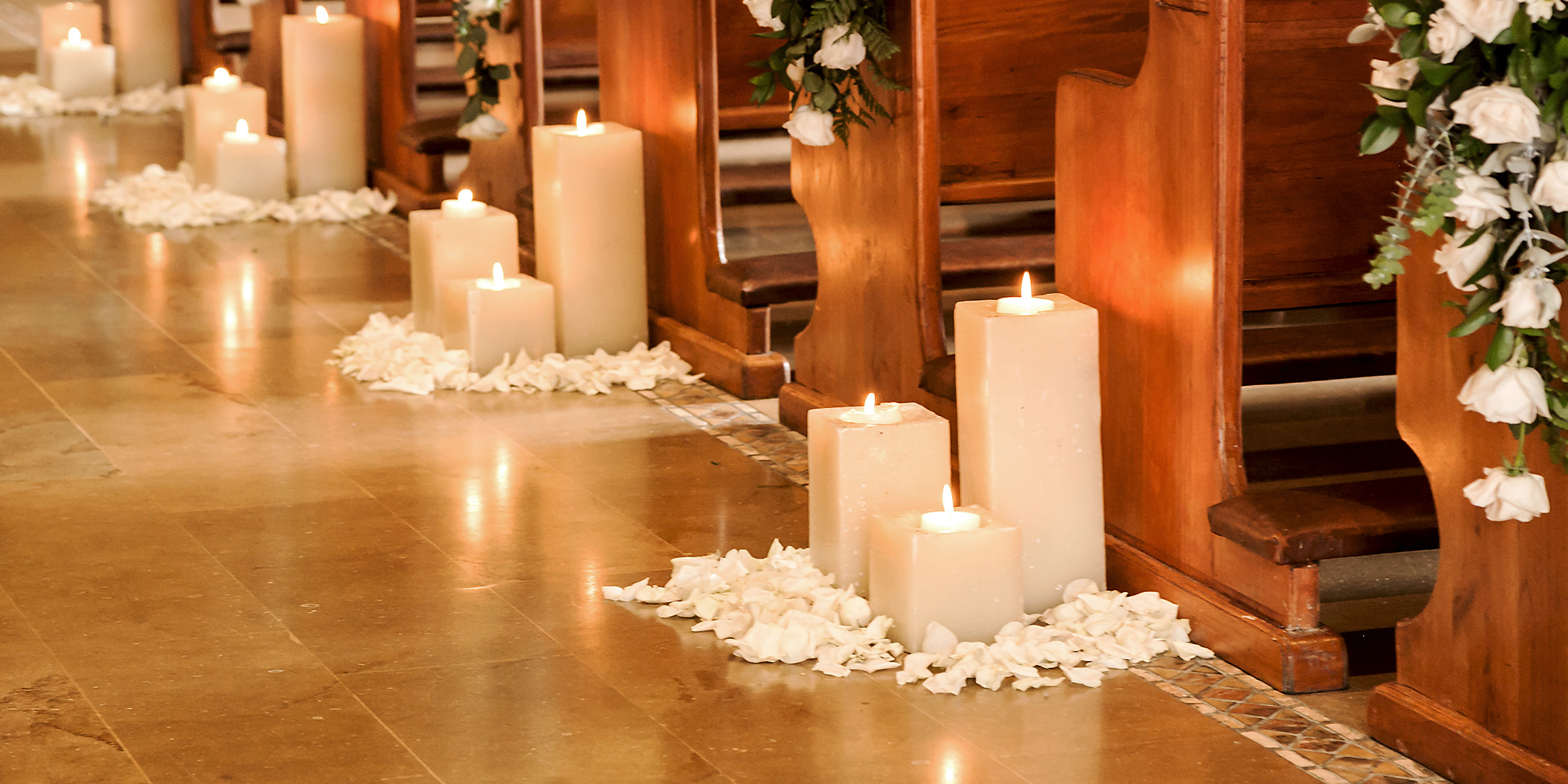 Soft candlelight line the aisle, scattered with white rose petals and framed by wooden pews | Source: Shutterstock