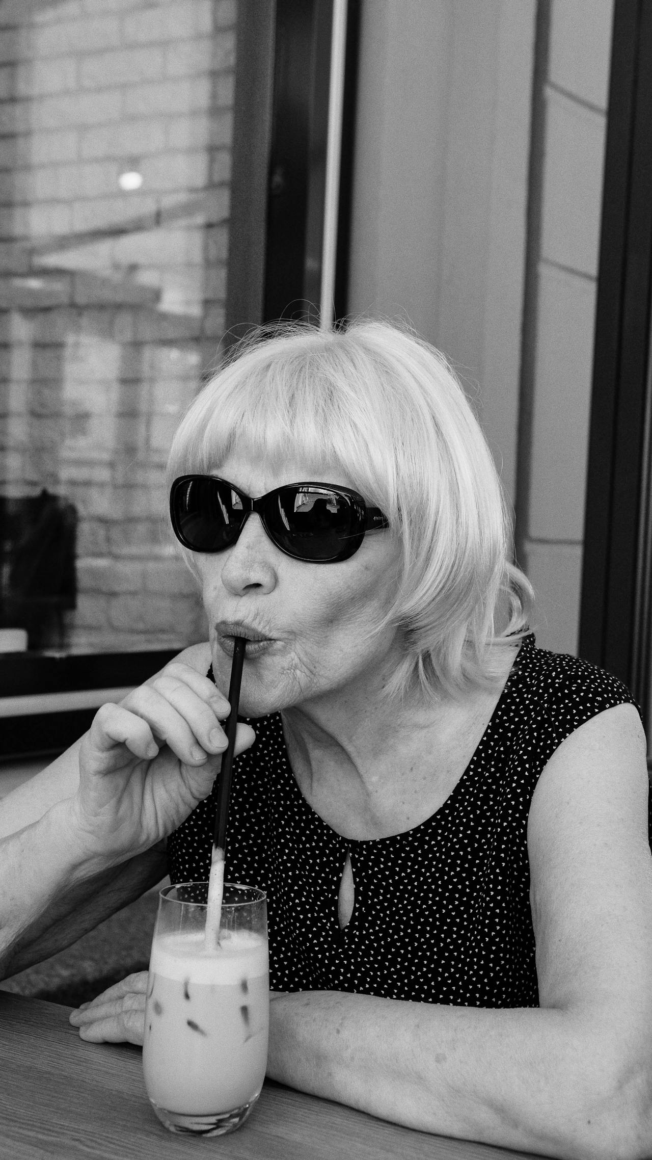 Grayscale shot of a senior woman drinking a glass of beverage | Source: Pexels