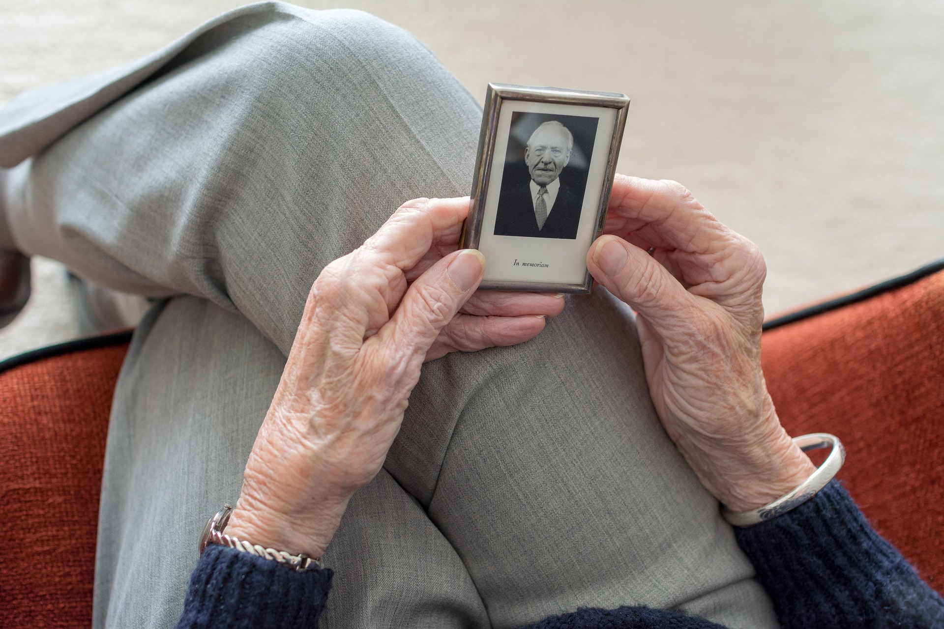 An older woman holding a framed photo of an older man | Source: Pixabay