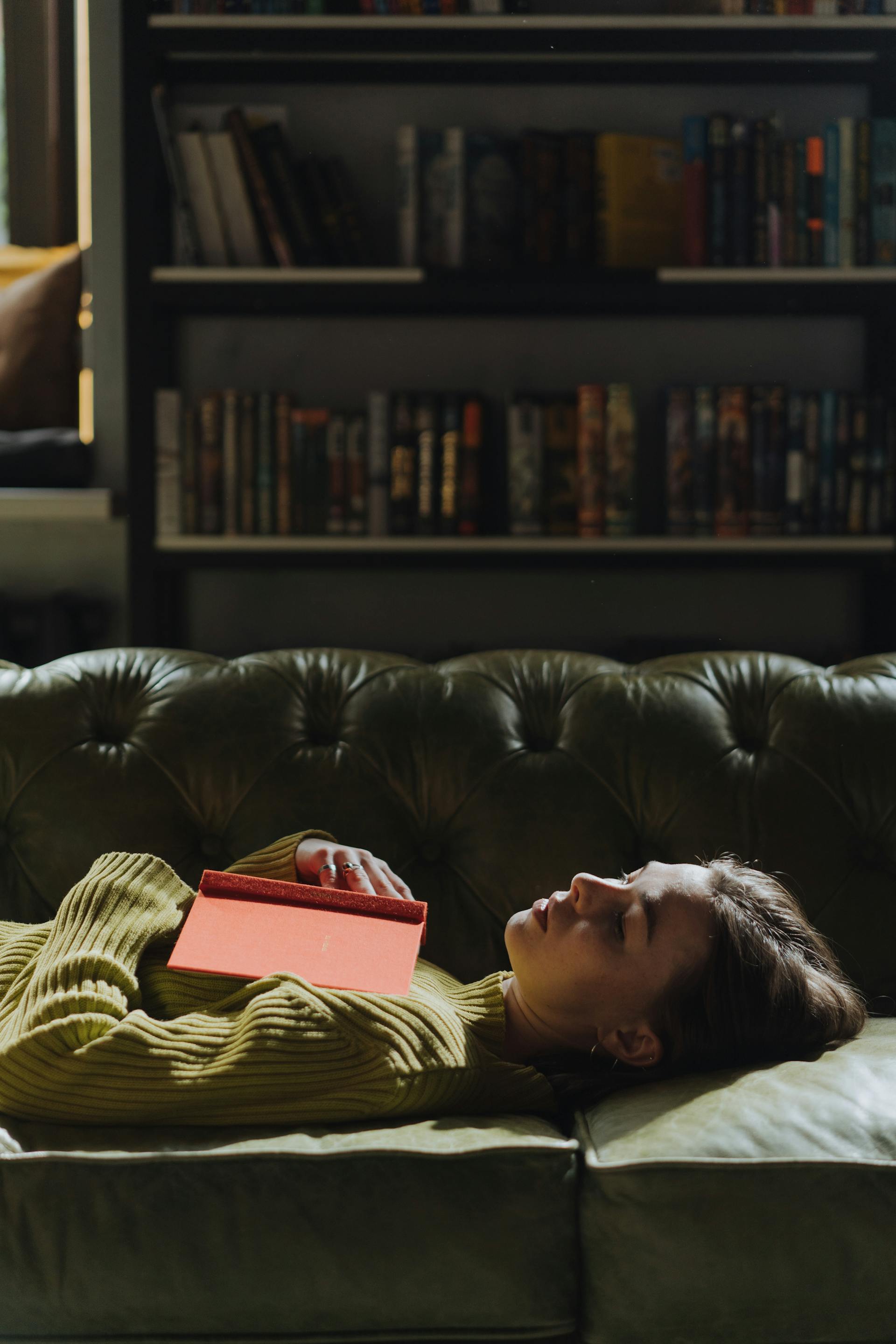 A woman lying on a sofa with a book | Source: Pexels