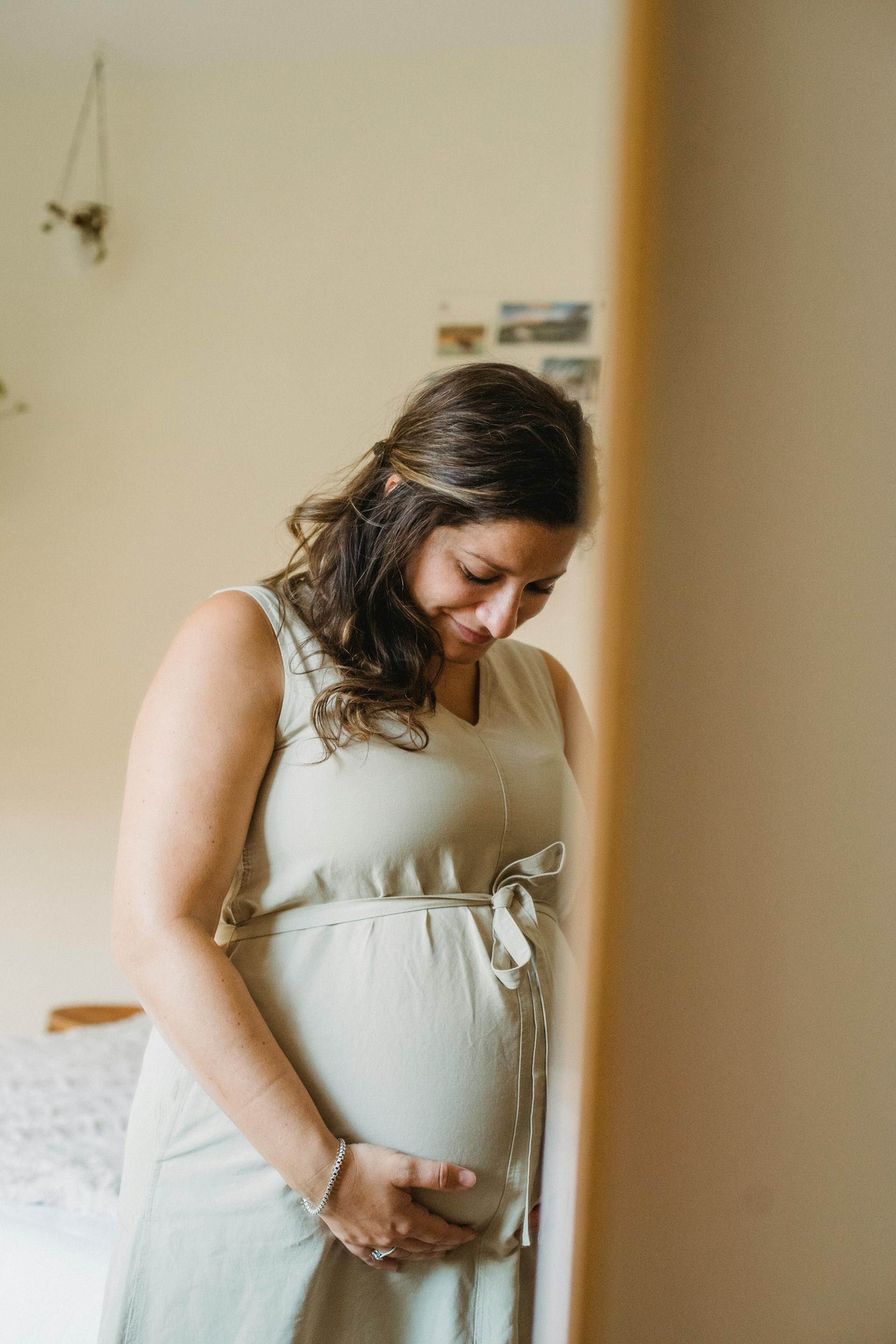 A woman smiling down at her pregnant belly | Source: Pexels