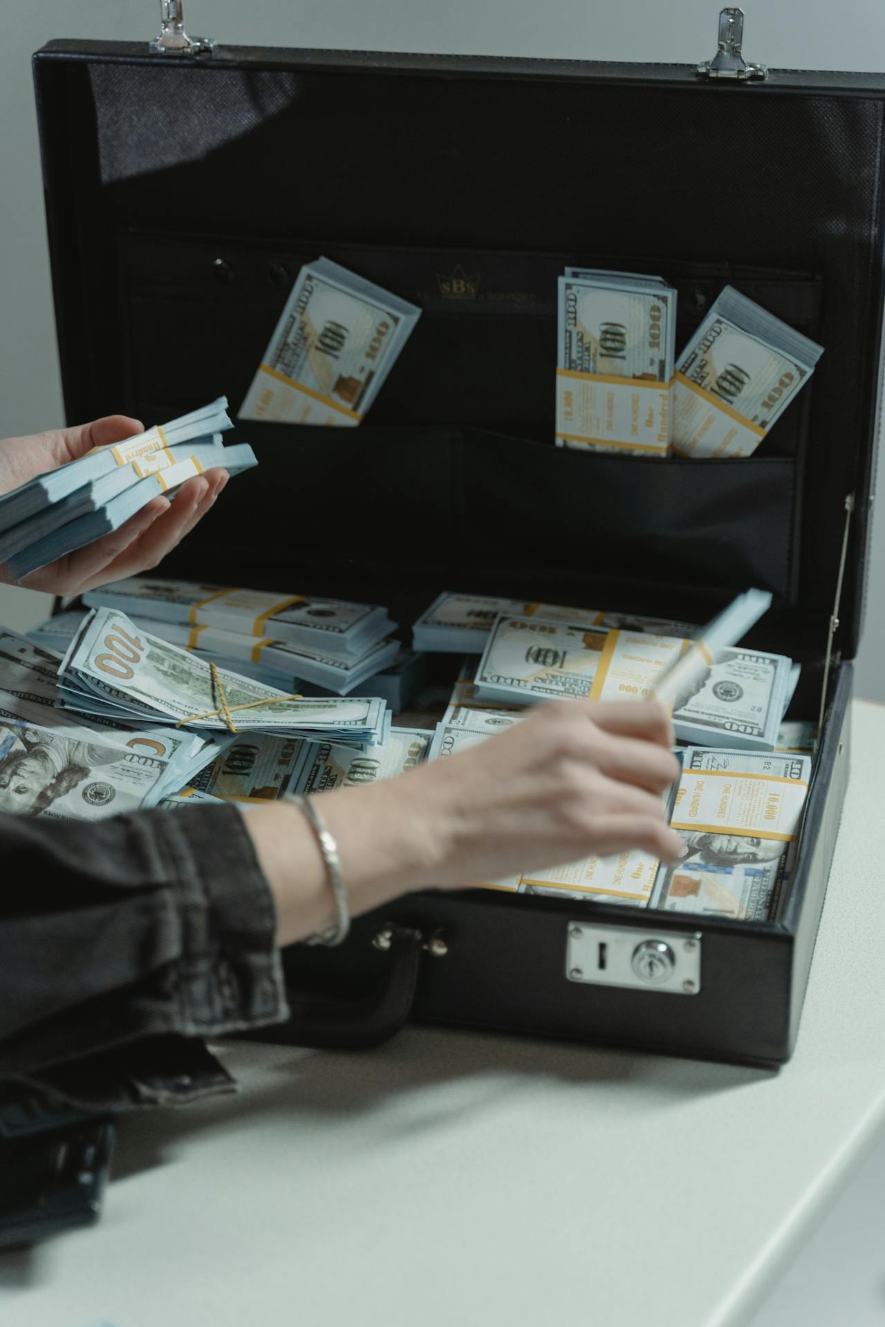 Cropped shot of a woman with a briefcase stashed with money | Source: Pexels