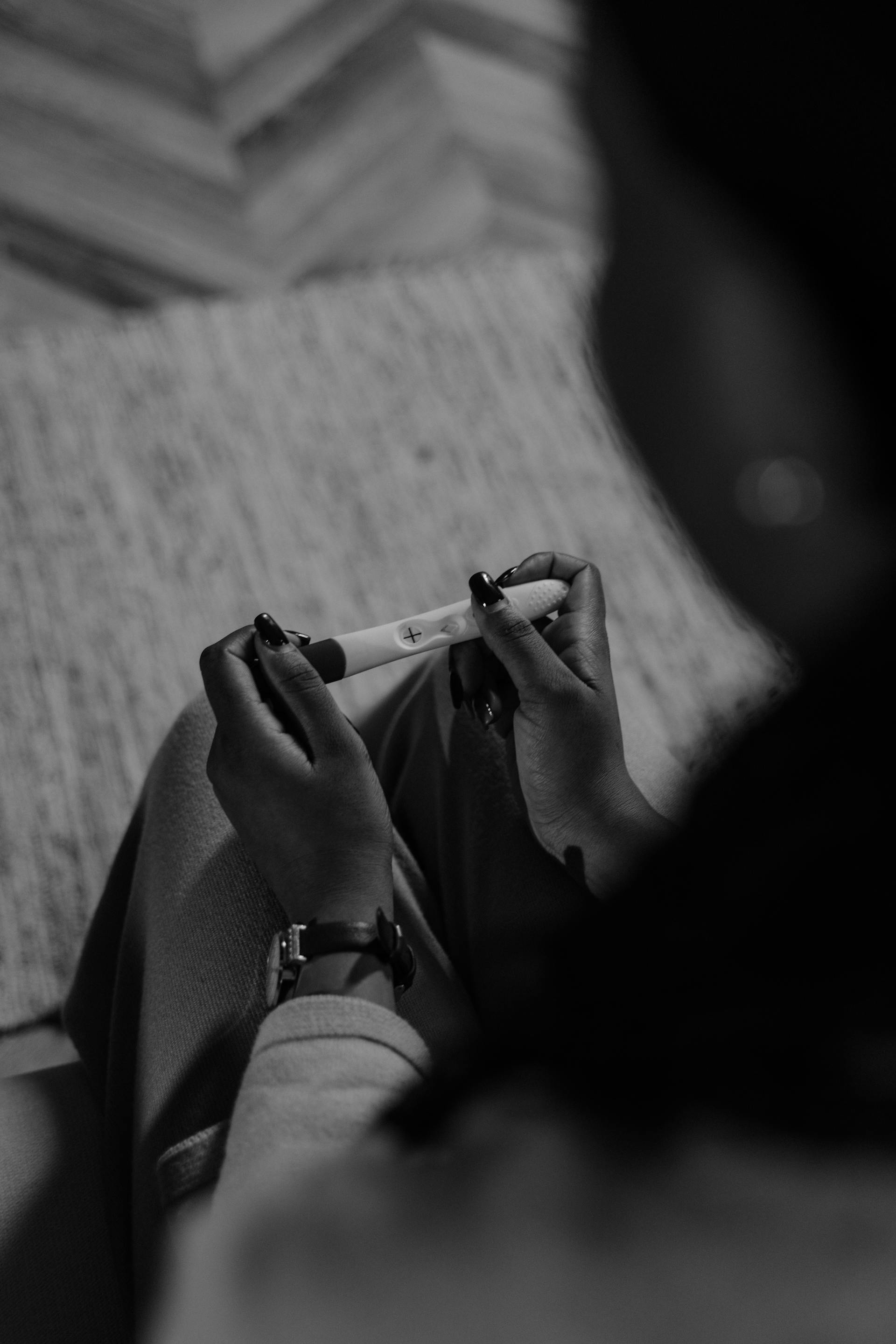 A grayscale photo of a woman looking at the result of a pregnancy test | Source: Pexels