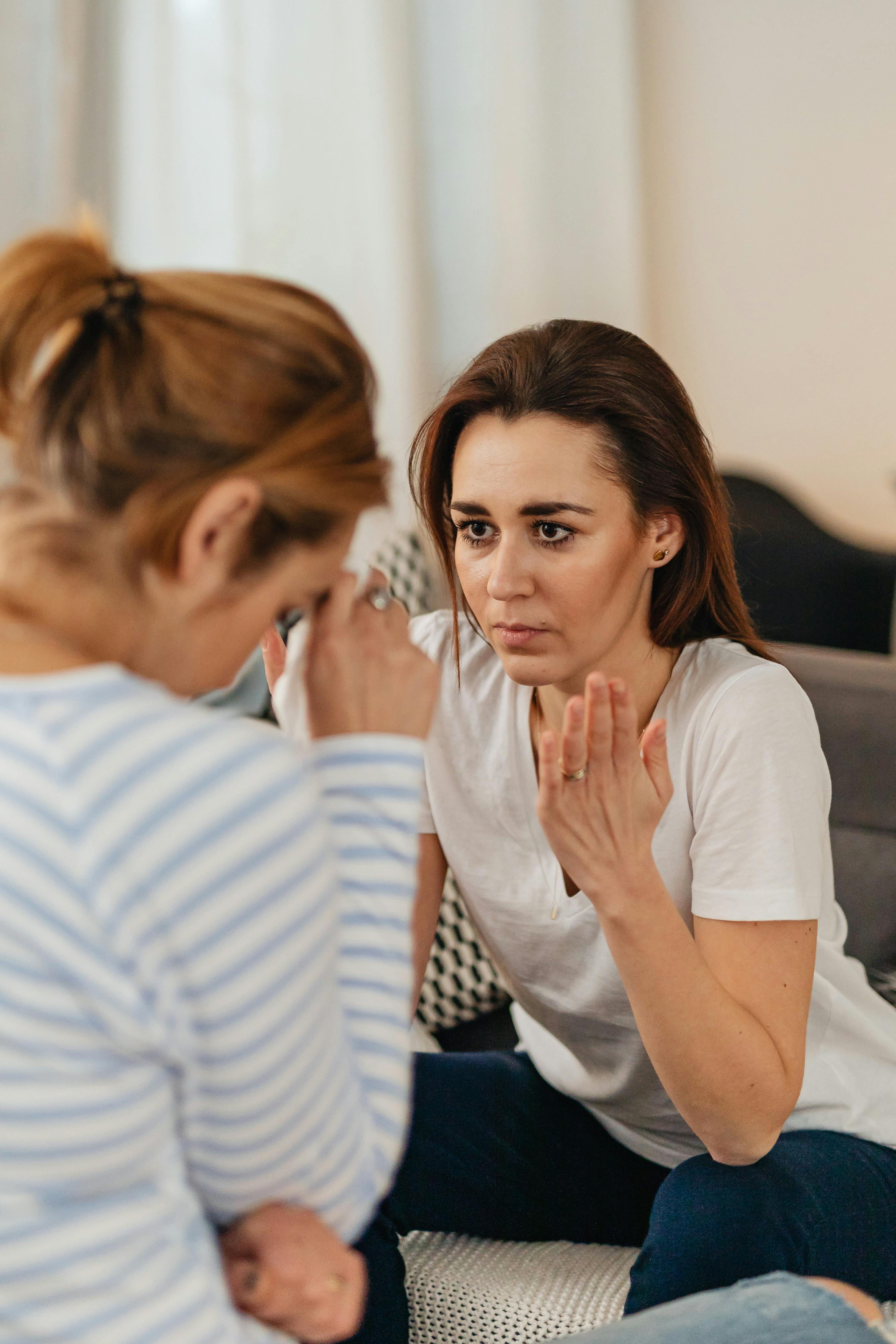 A woman talking while another has her face lowered | Source: Pexels