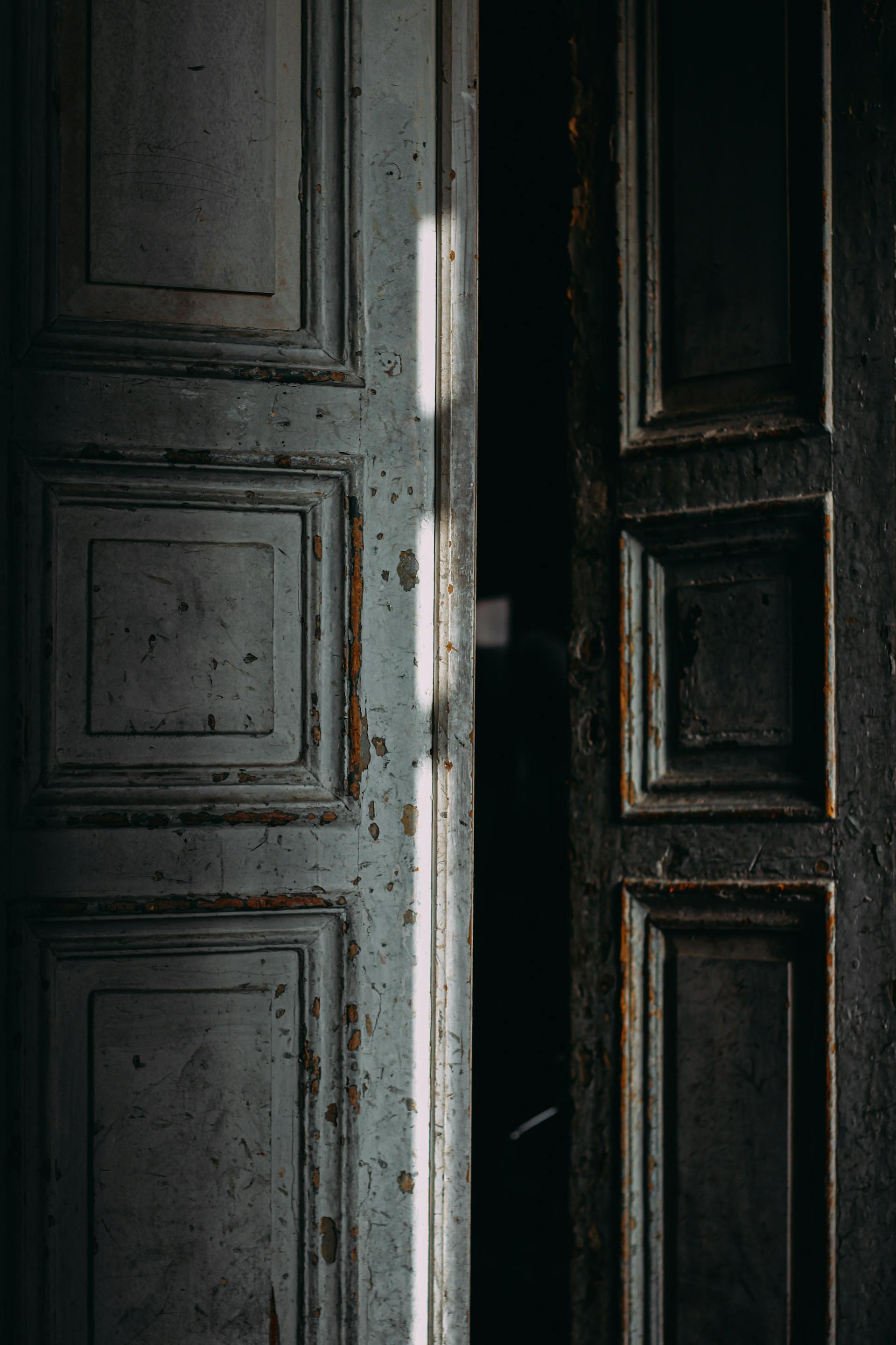 A slightly open door with peeling paint | Source: Pexels