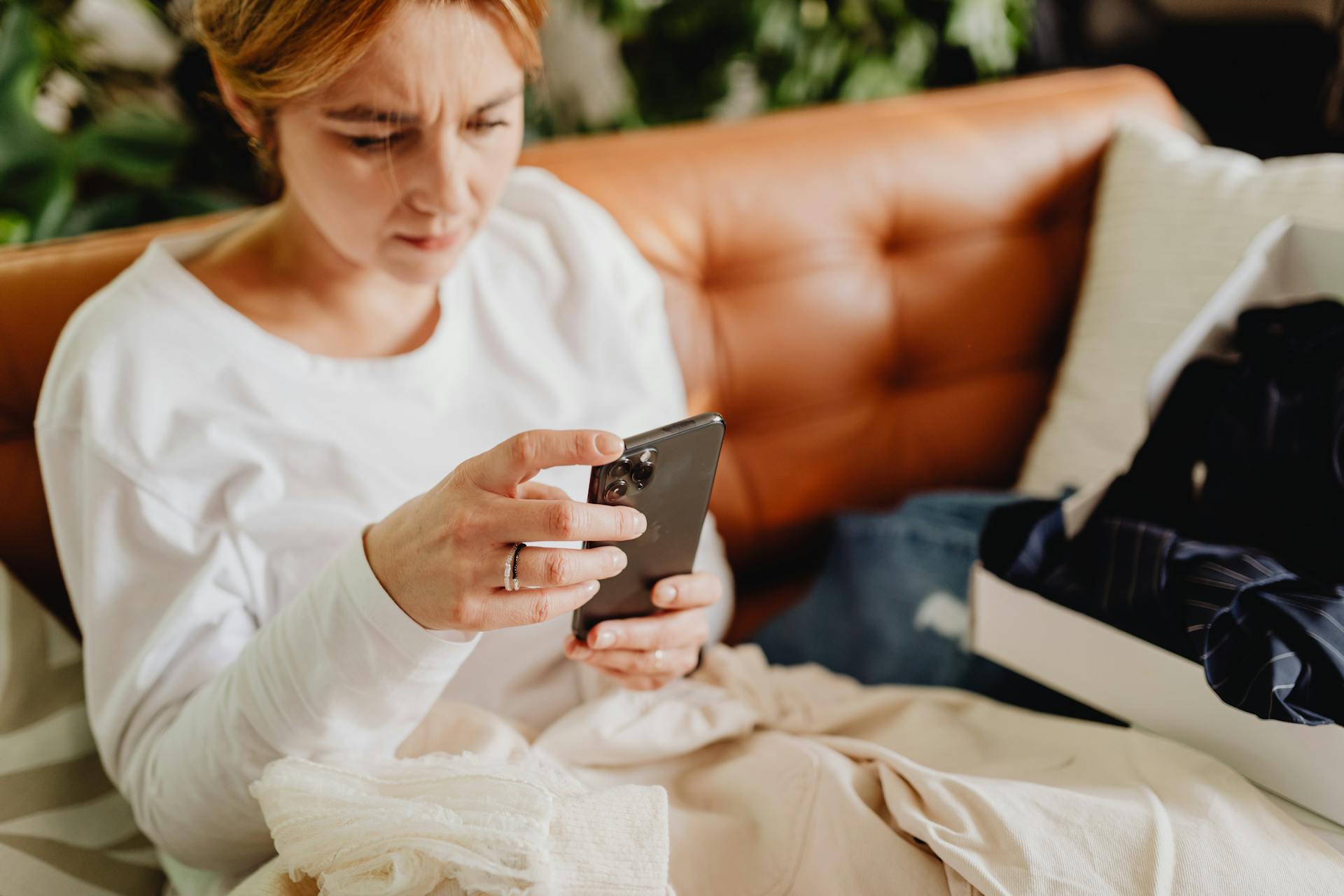 A woman sitting on the couch and holding her smartphone | Source: Pexels