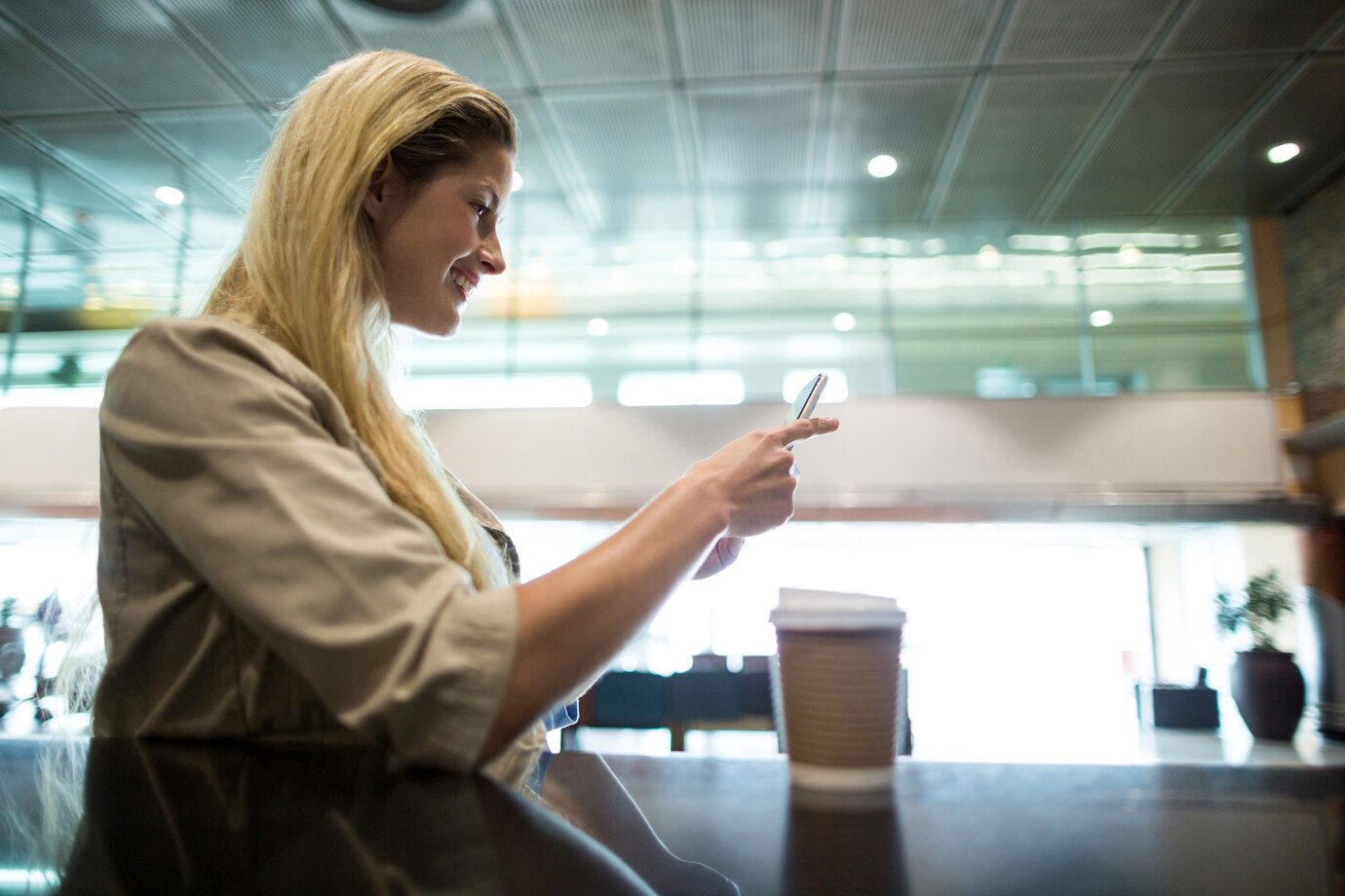 A woman on her phone in an airport | Source: Freepik