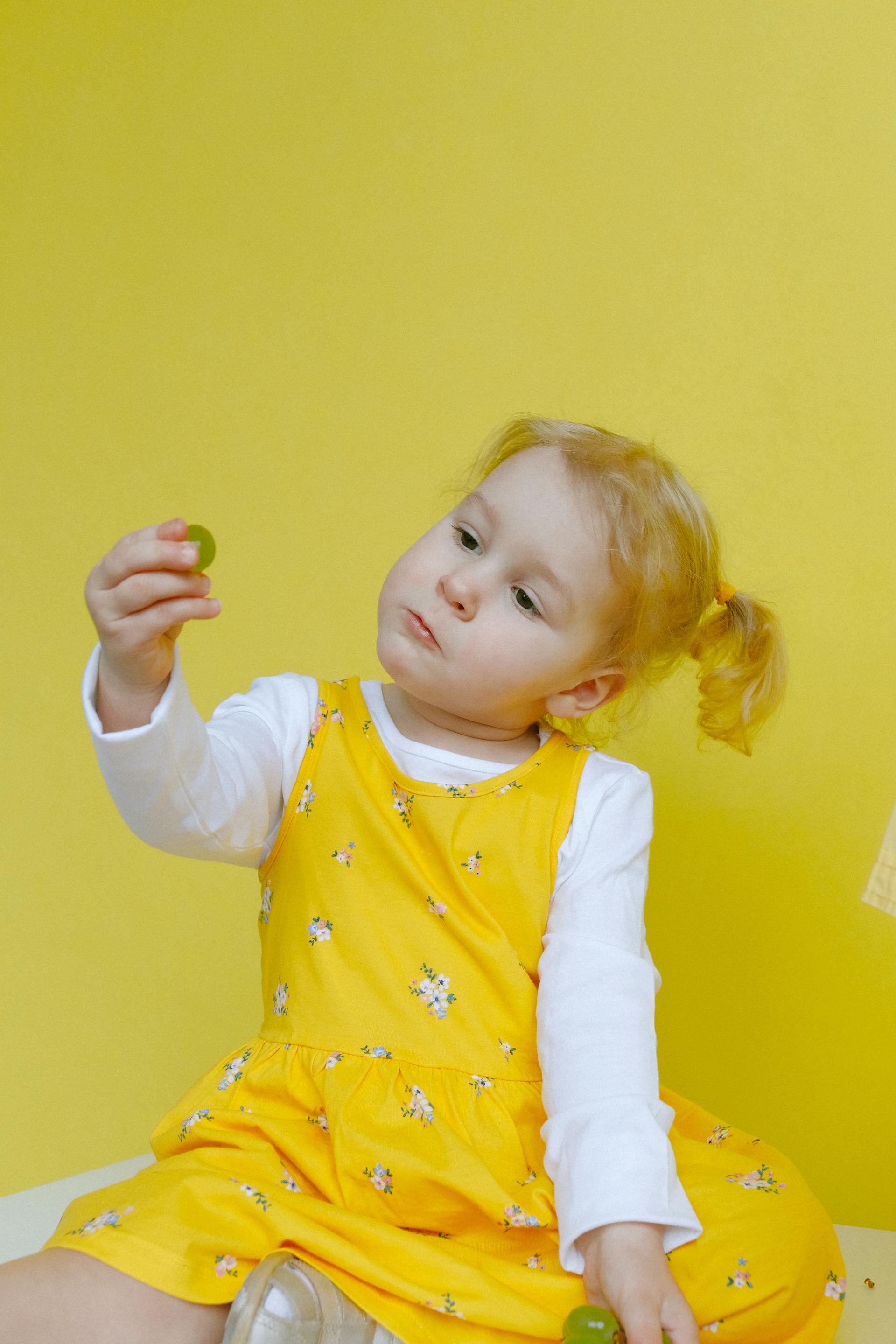 A little girl looking at a ball in her hand | Source: Pexels