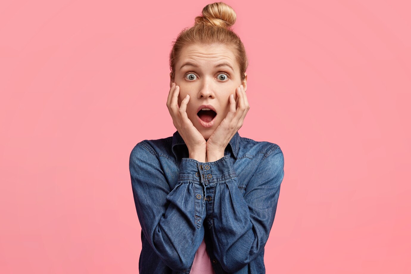 A shocked woman against a pink backdrop | Source: Freepik