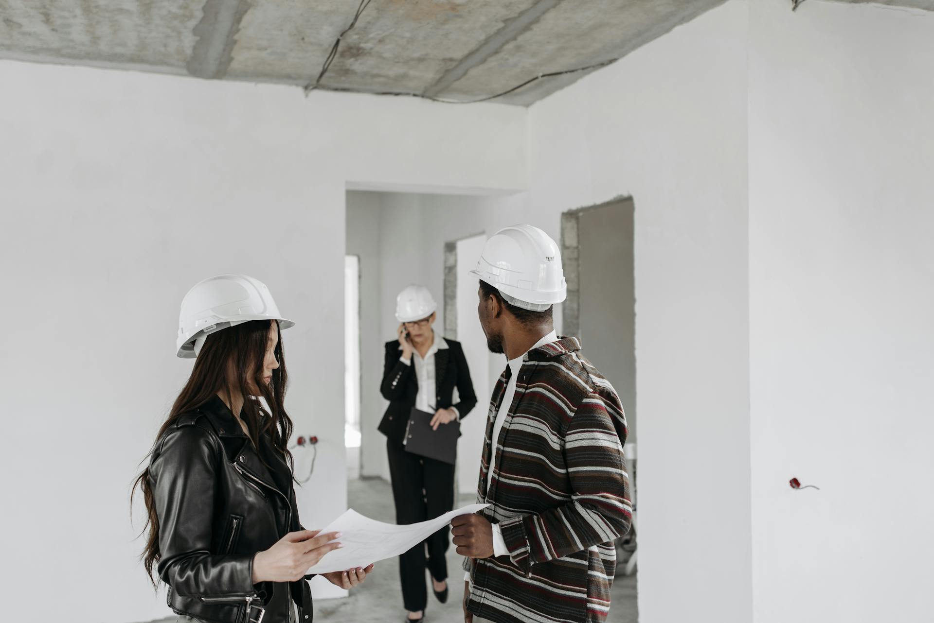 Contractors discussing paper work on site | Source: Pexels
