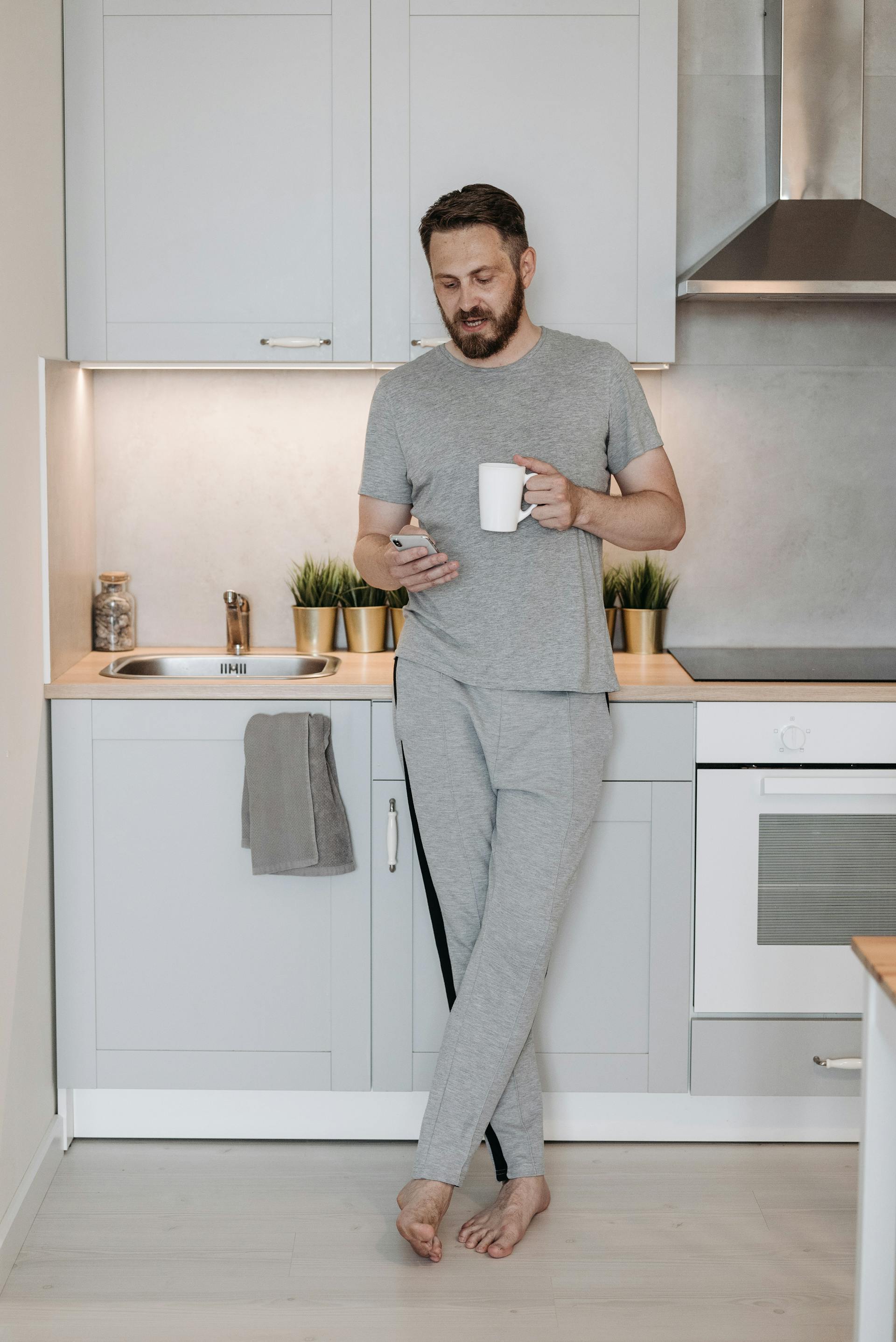 A man scrolling on his phone in a kitchen | Source: Pexels