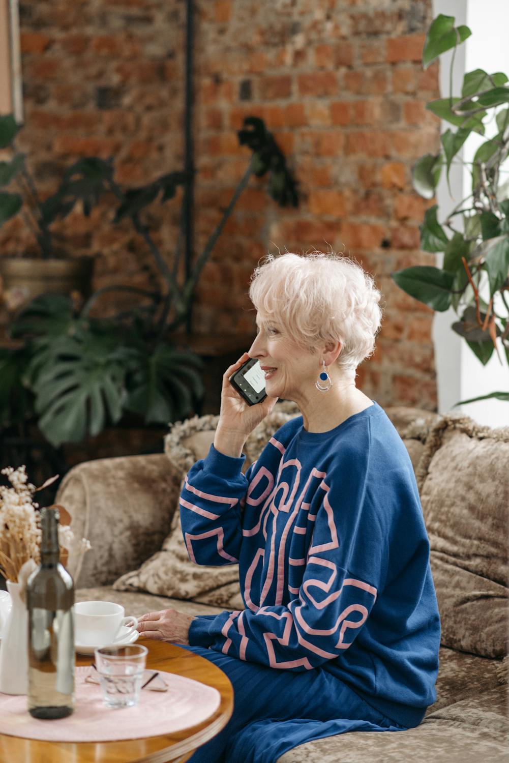 A smiling woman talking on her phone in her living room | Source: Pexels